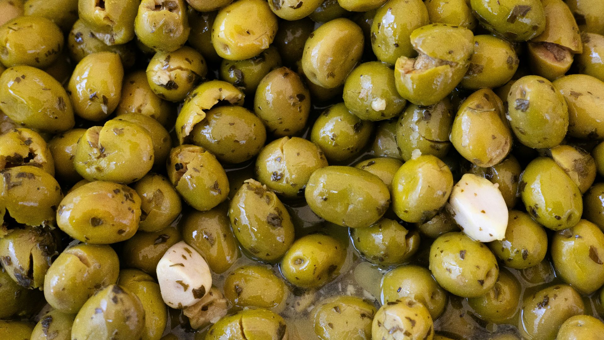 a pile of green olives with brown spots on them