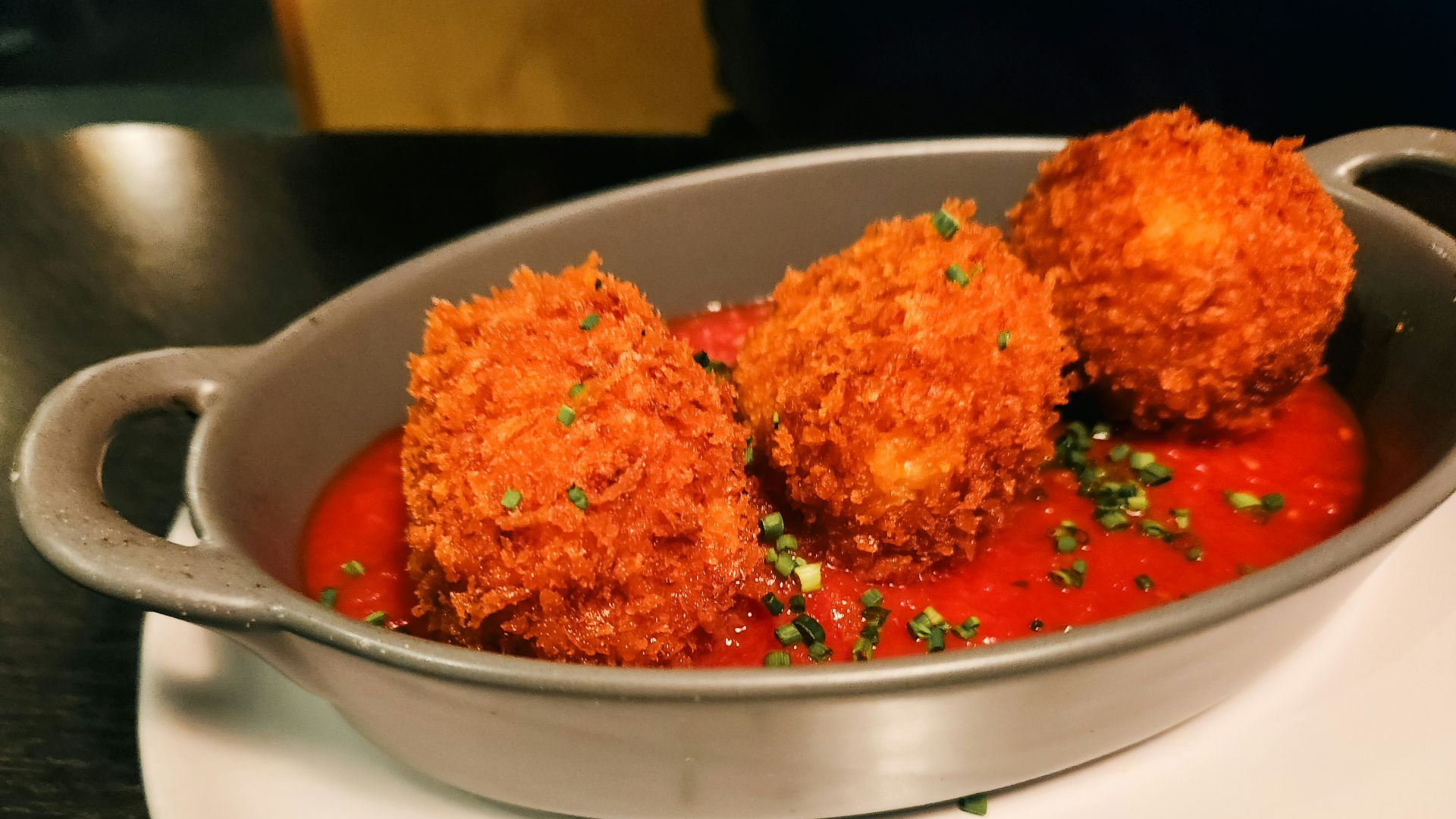 Fried food balls with tomato sauce are served.