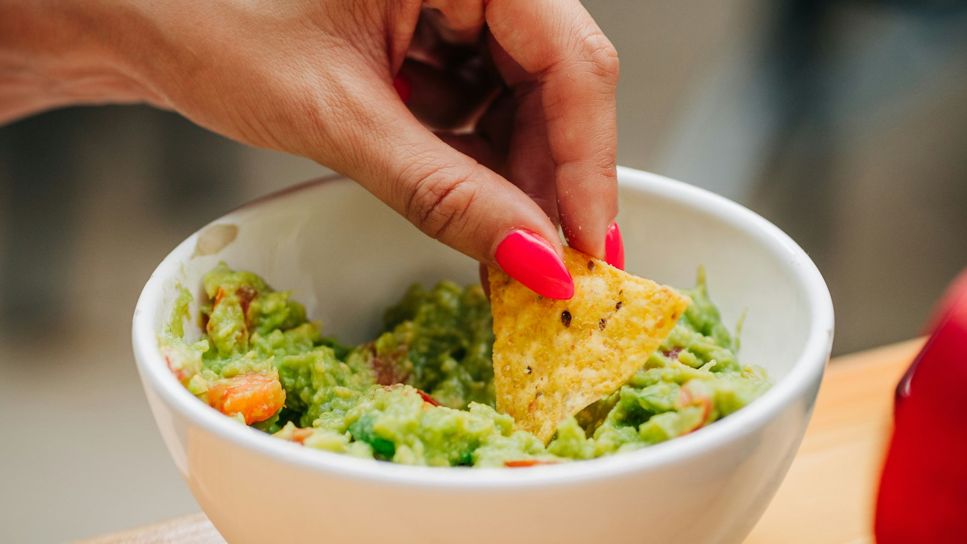 a person dipping a tortilla into a bowl of guacamole