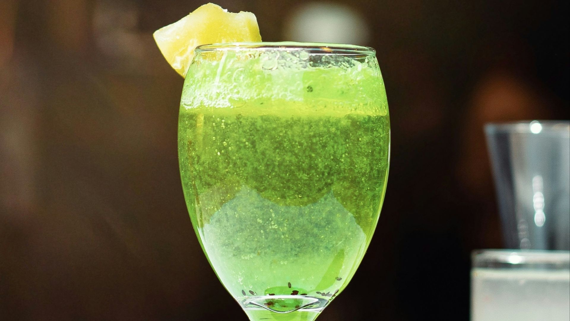 a green drink with a slice of lemon on the rim