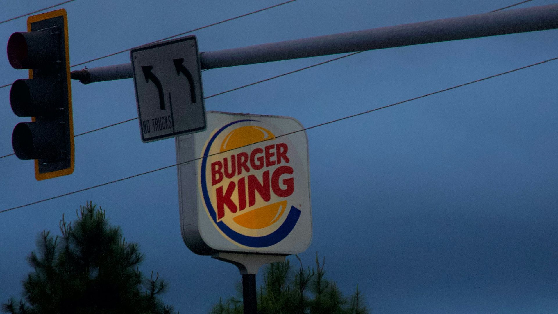 a burger king sign and traffic lights on a cloudy day