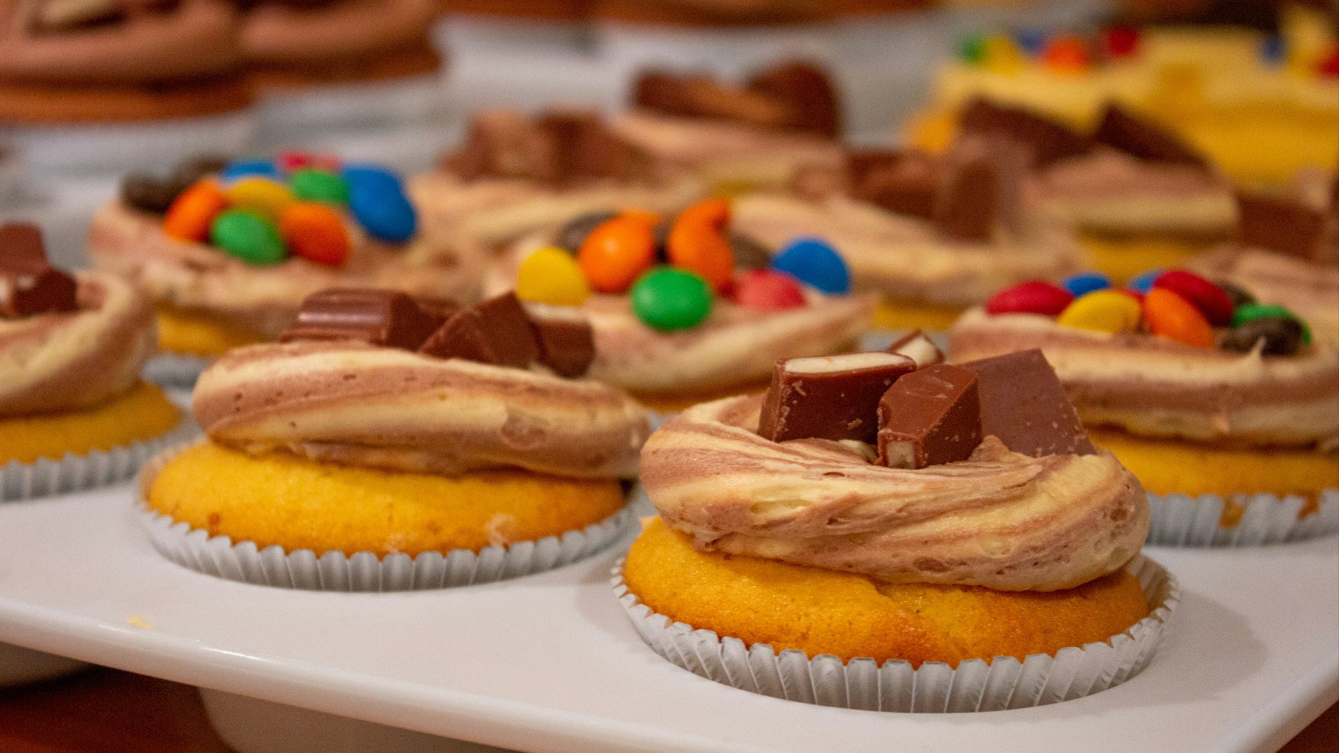 a tray of cupcakes with frosting and candy on top