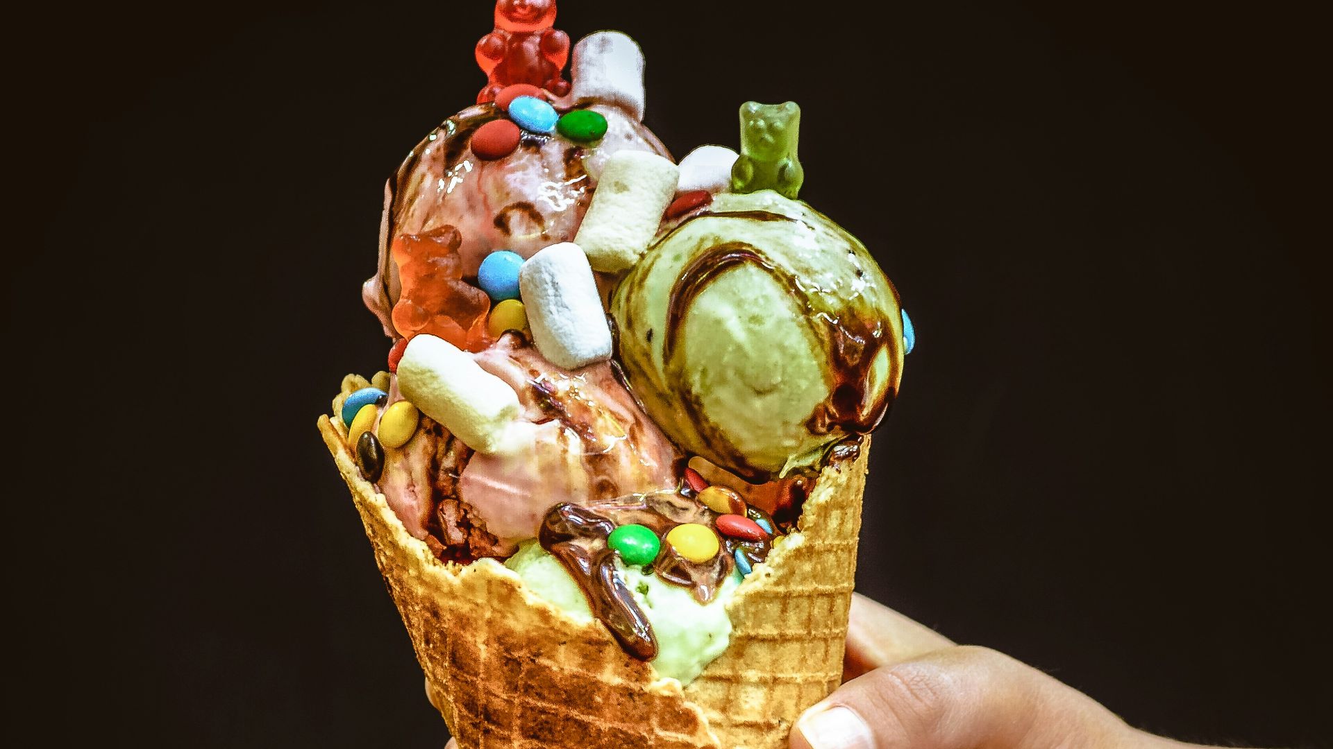 a hand holding an ice cream cone filled with lots of toppings