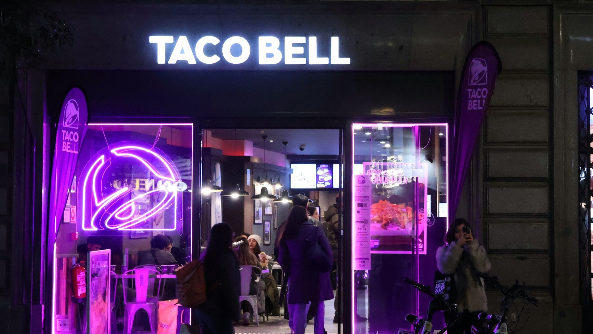 A purple lit store front with people walking by