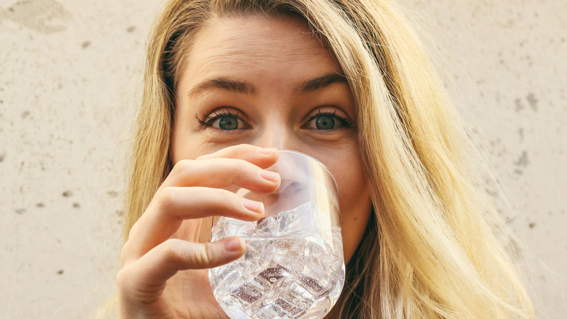 woman in white crew neck shirt drinking water