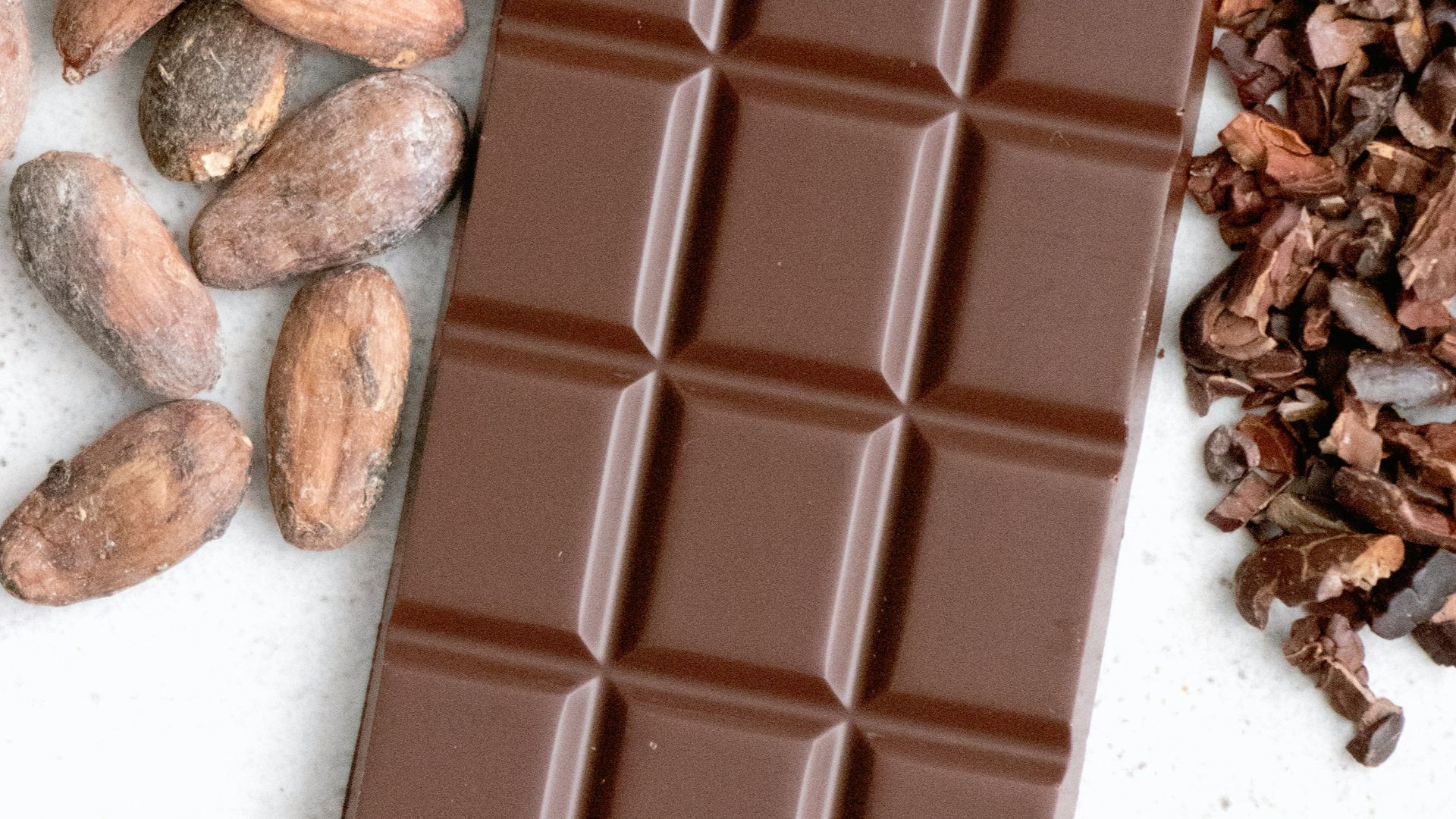 a bar of chocolate next to a pile of nuts