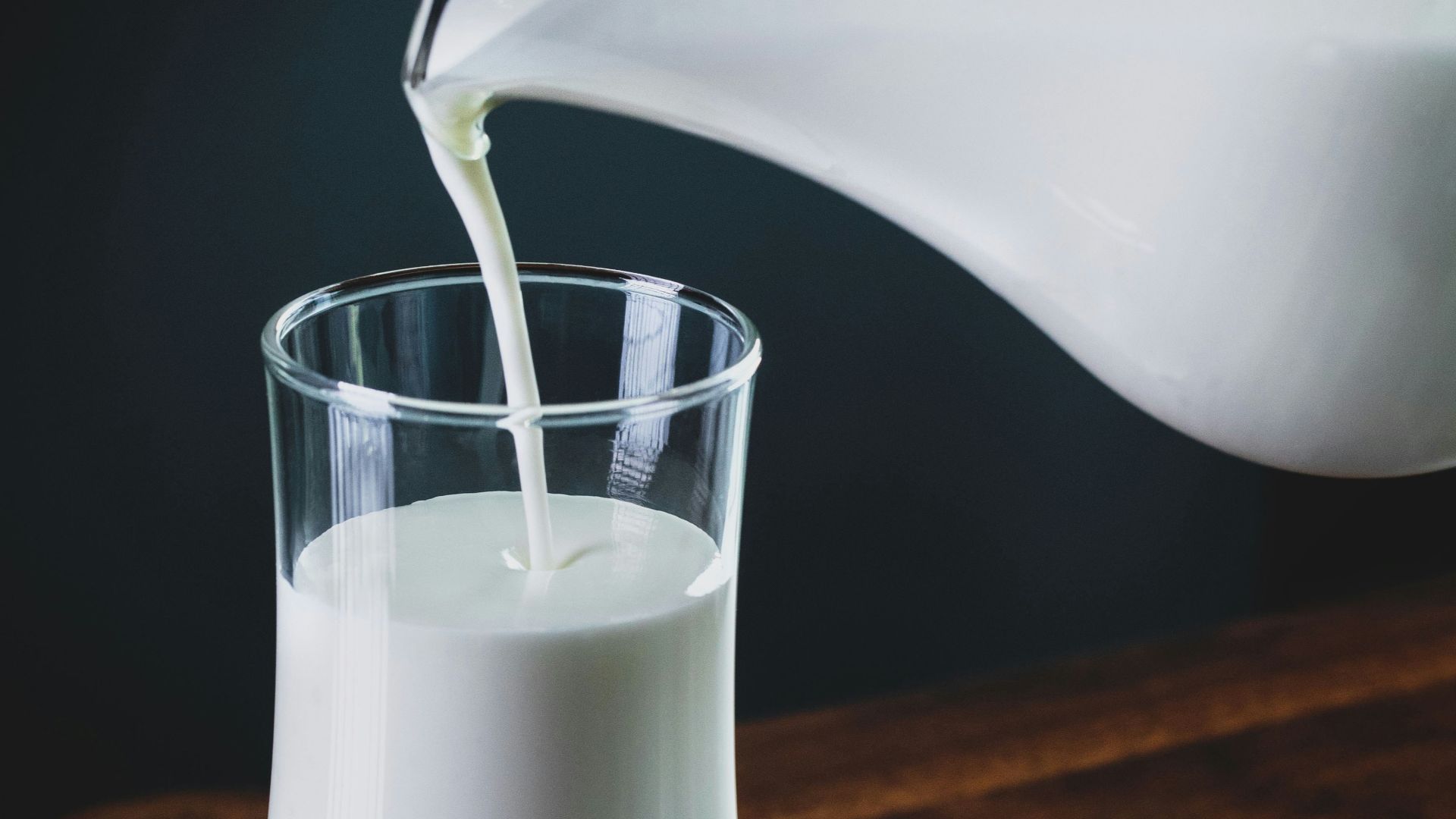 person pours milk into glass