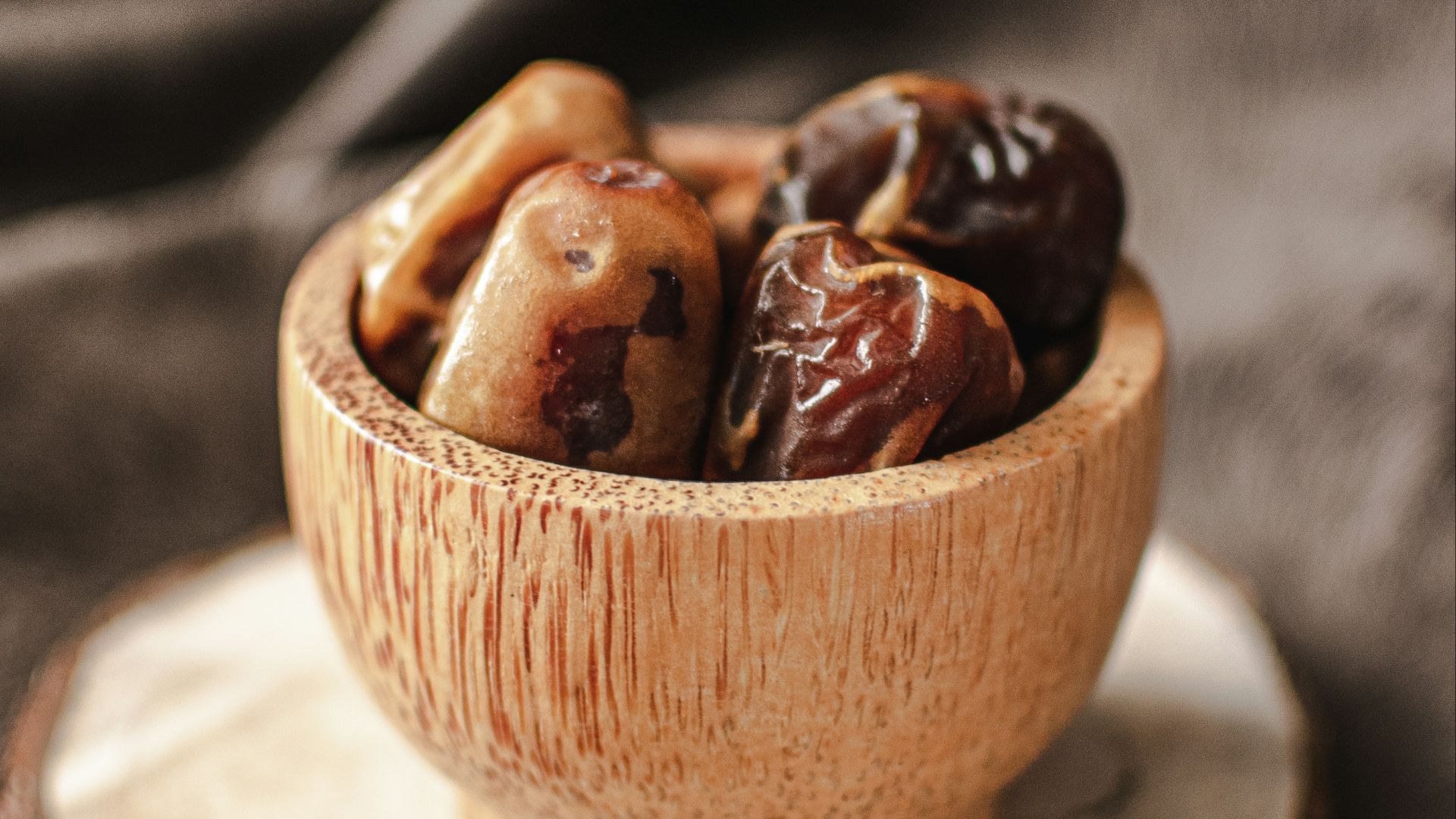 a wooden bowl filled with nuts on top of a wooden plate