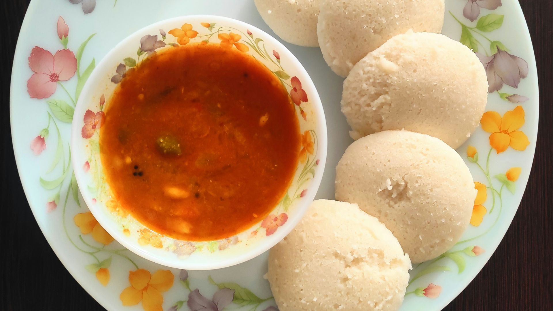 a white plate topped with three dumplings and a bowl of sauce