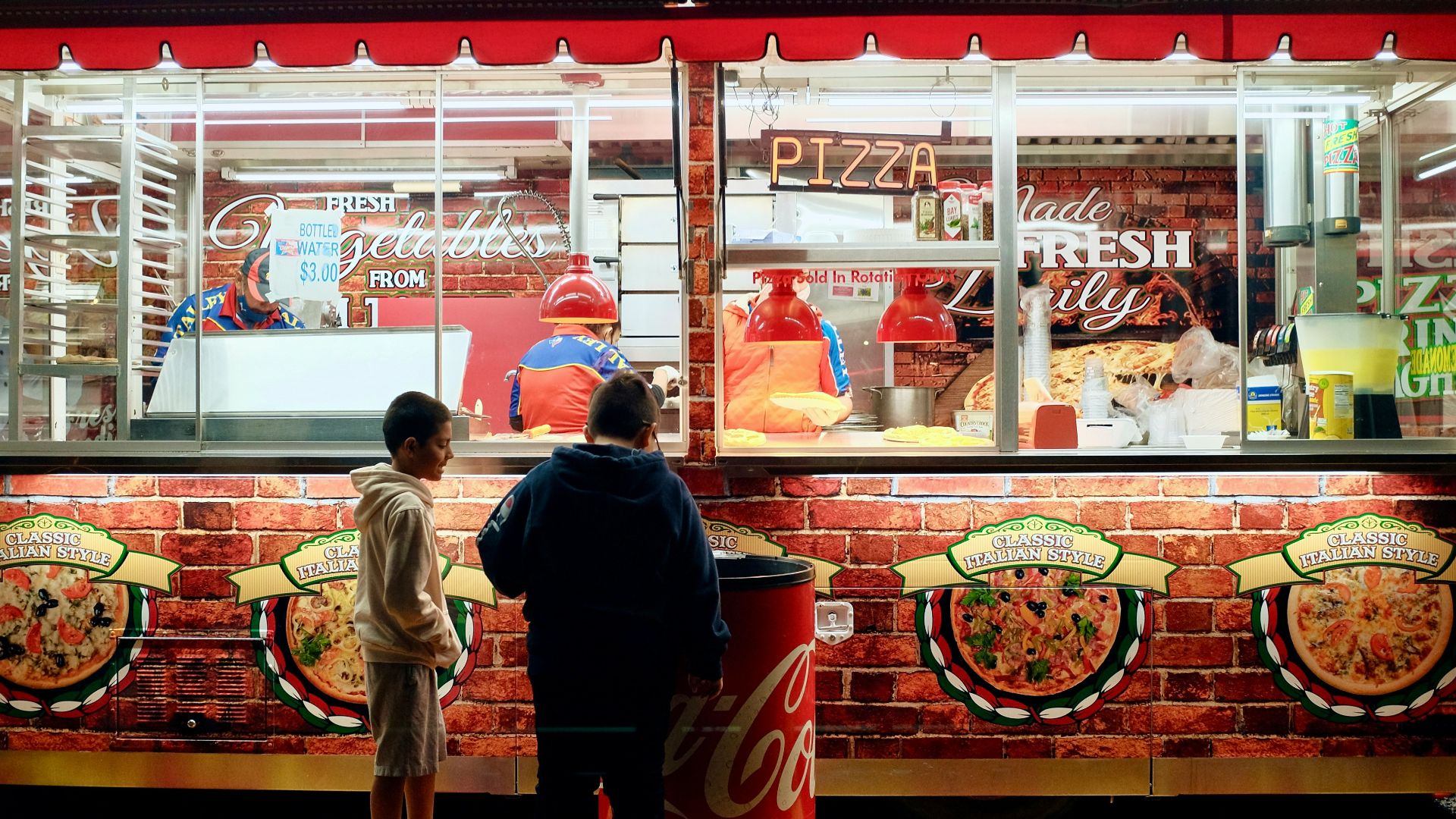 man in black jacket standing in front of food stall