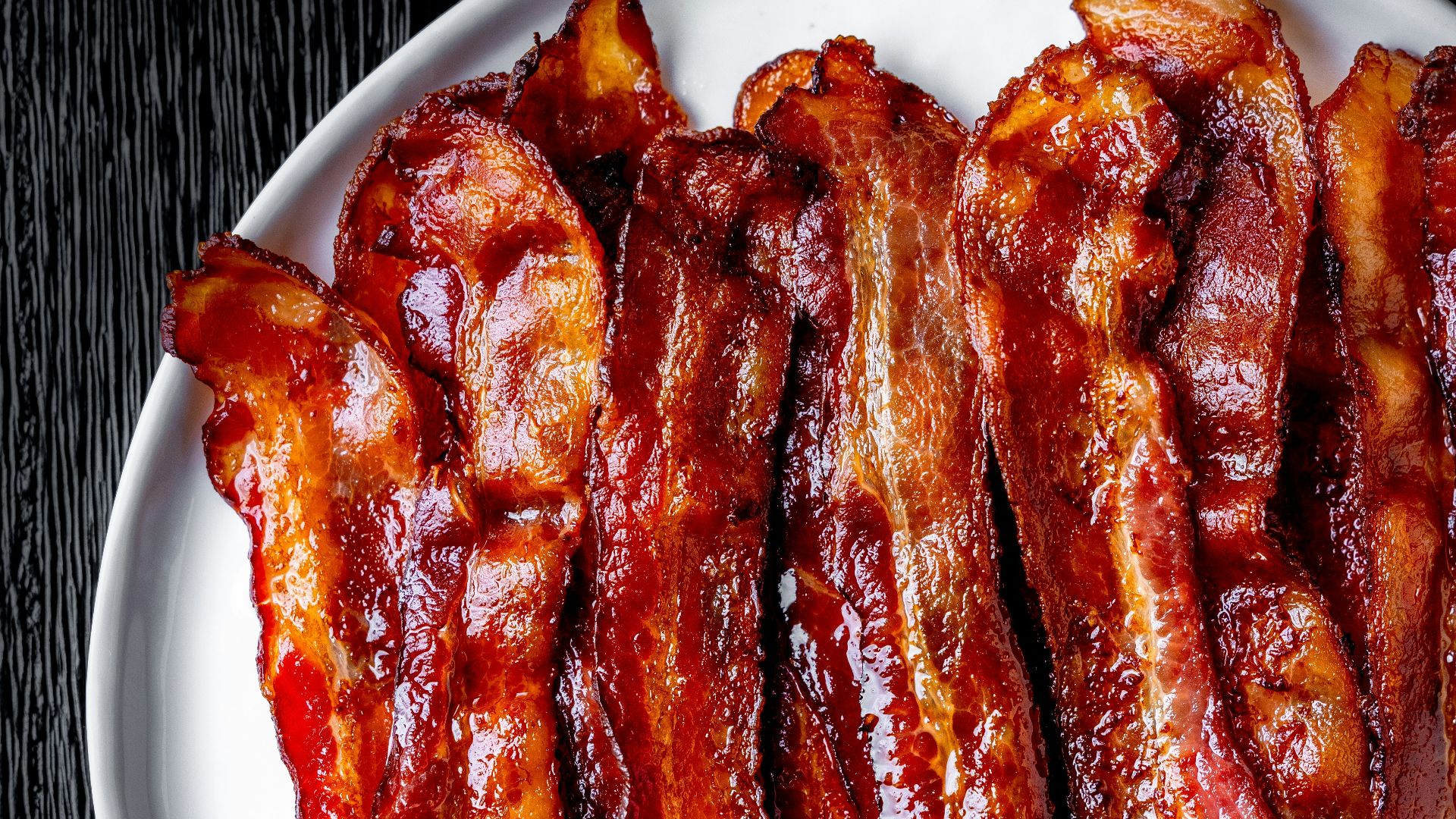a white plate topped with bacon strips on top of a table