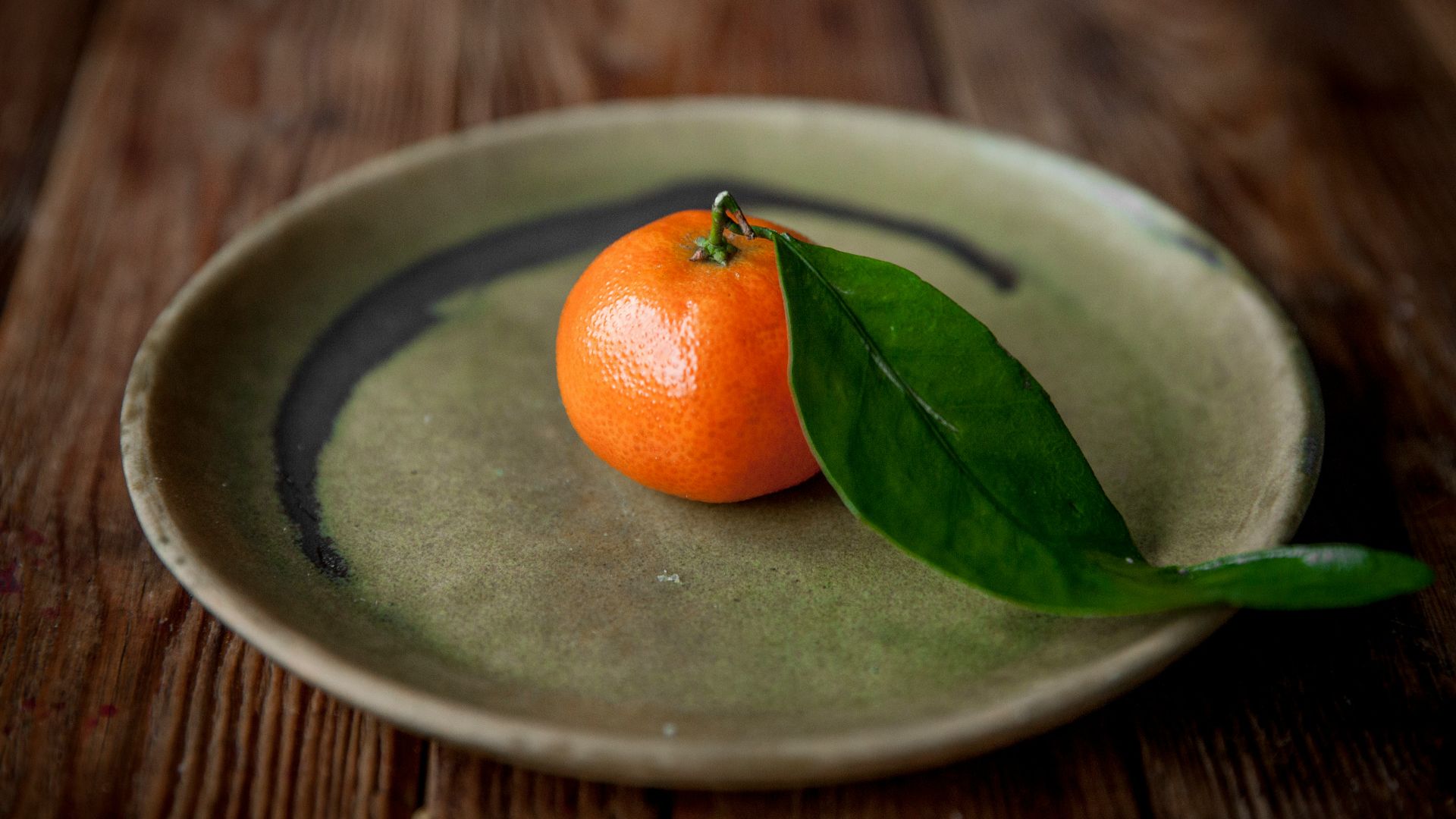 an orange and a leaf on a plate