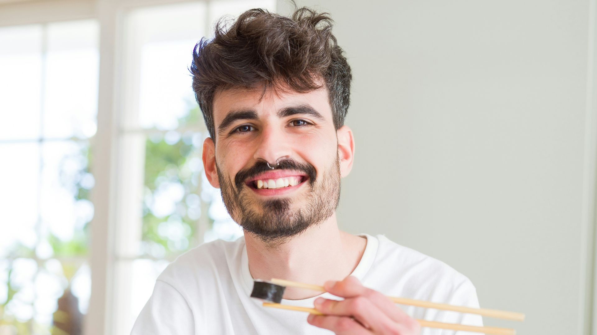 man in white crew neck t-shirt holding white chopsticks