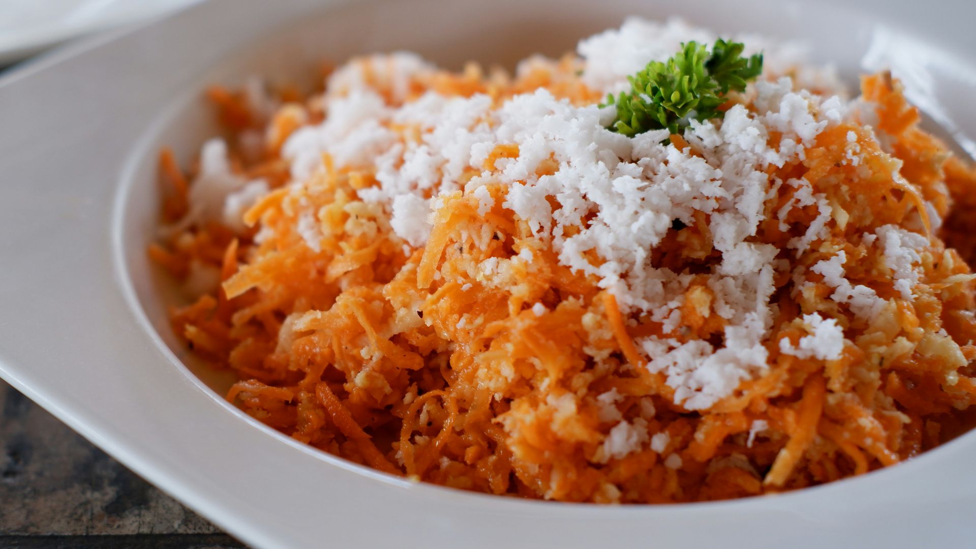 a bowl of shredded carrots with parmesan cheese