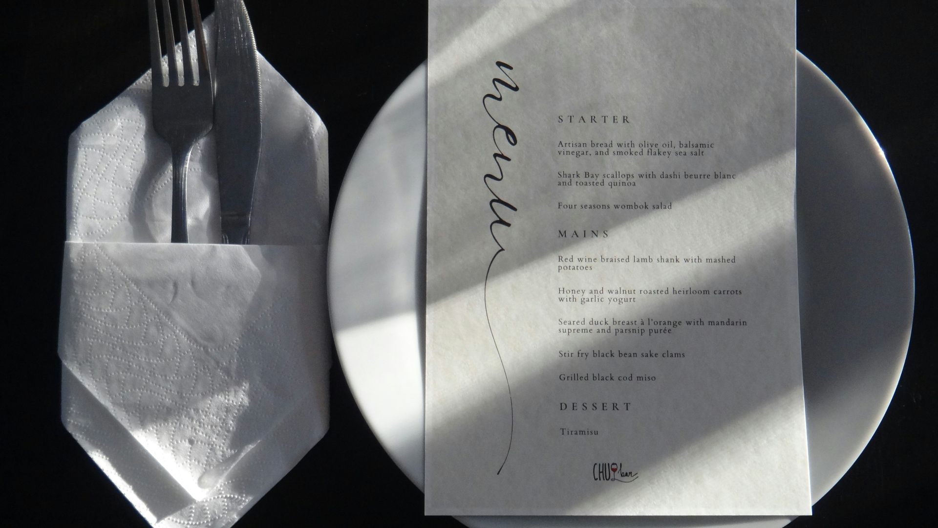 A white plate topped with a piece of paper next to a fork and knife