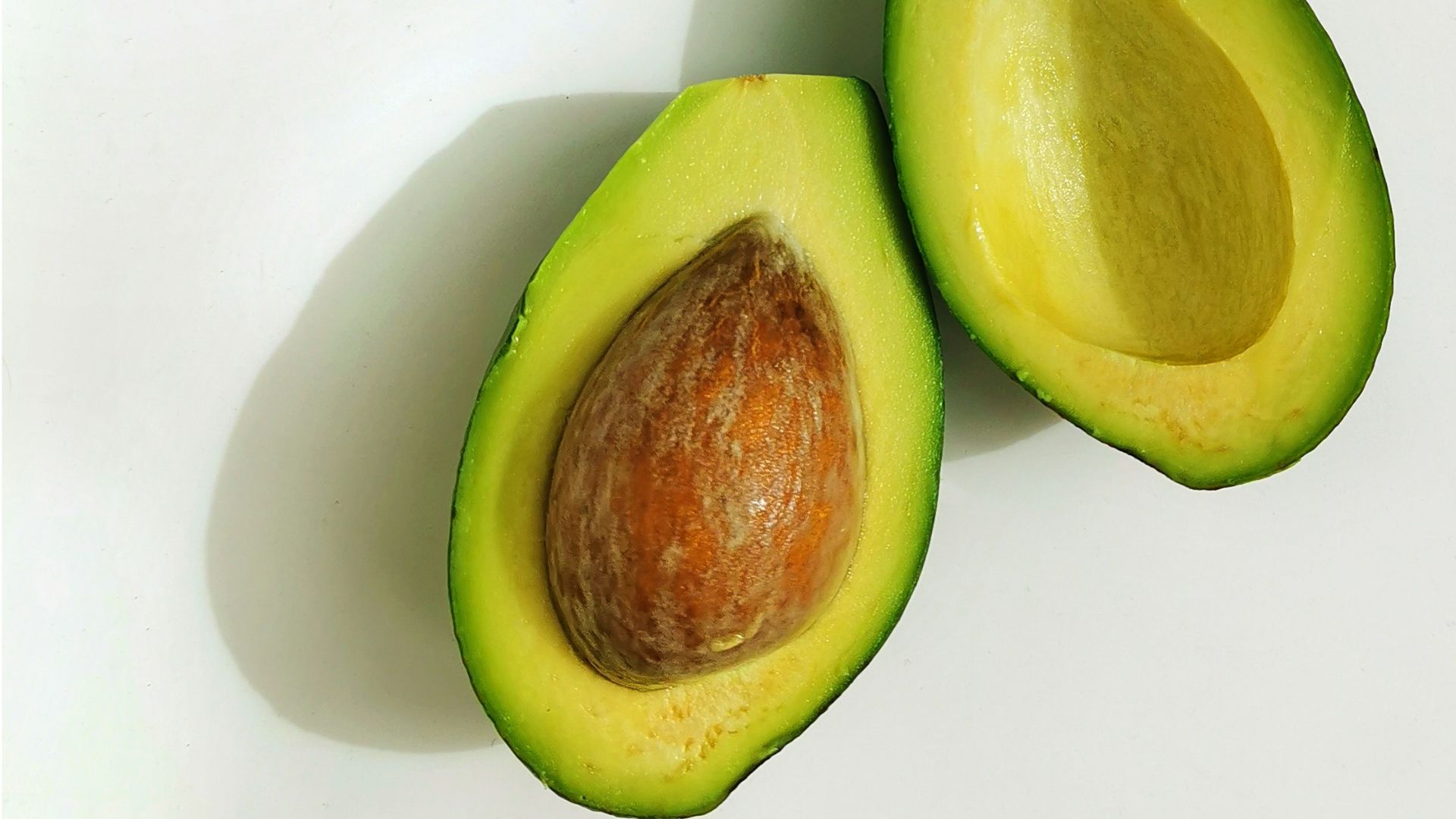 an avocado cut in half on a white surface