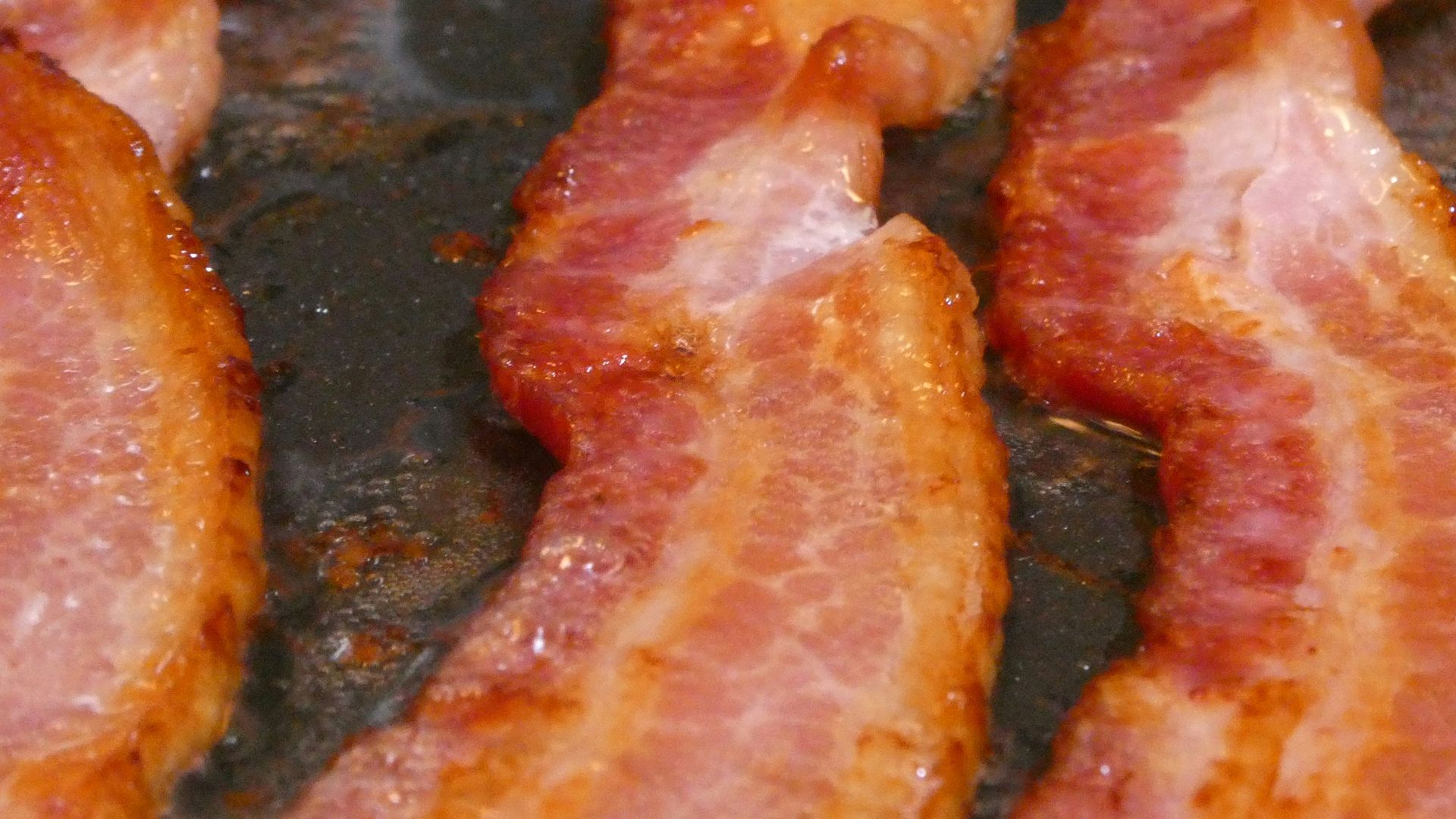 bacon is being cooked in a frying pan