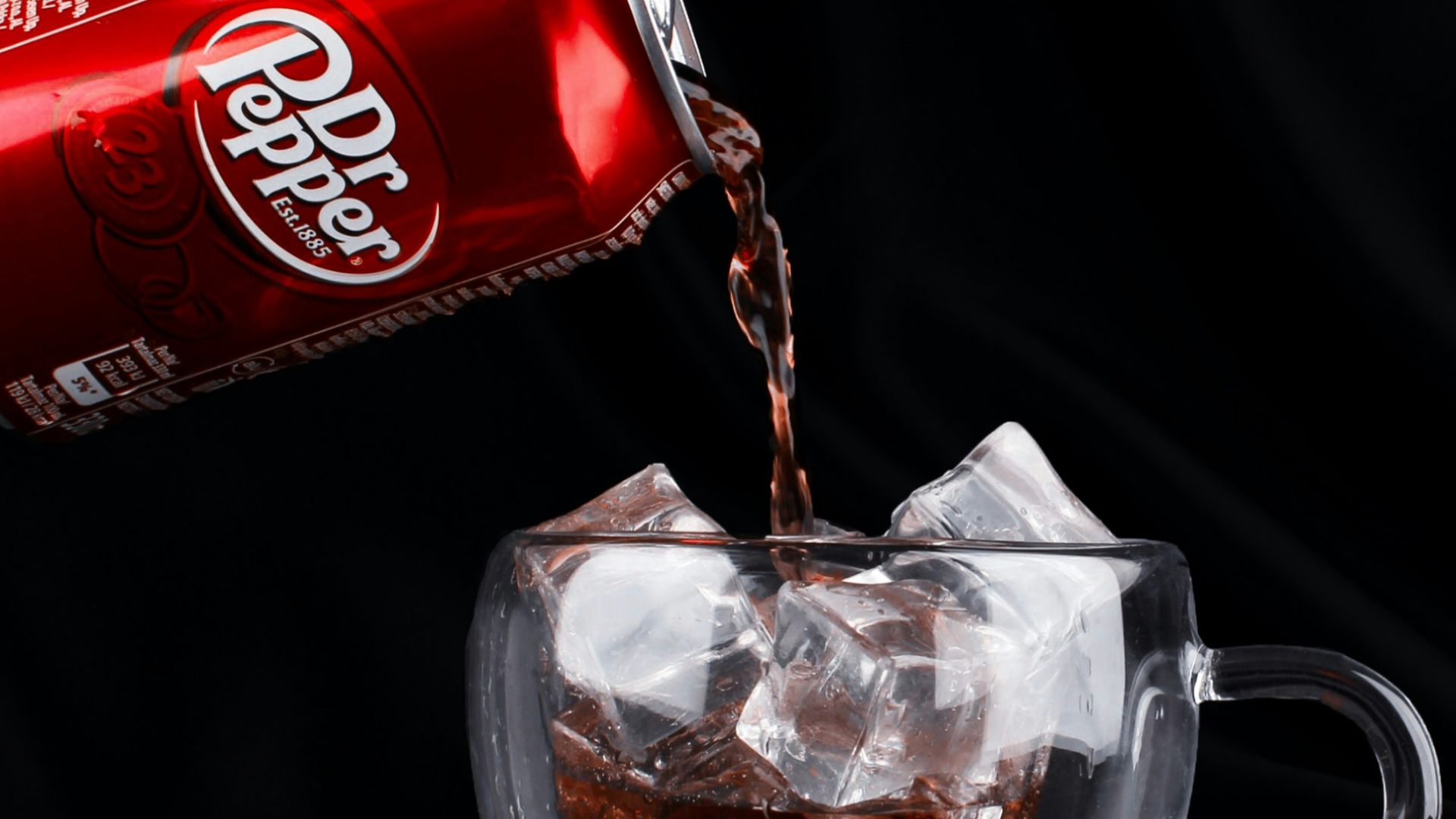 A can of coca cola being poured into a cup