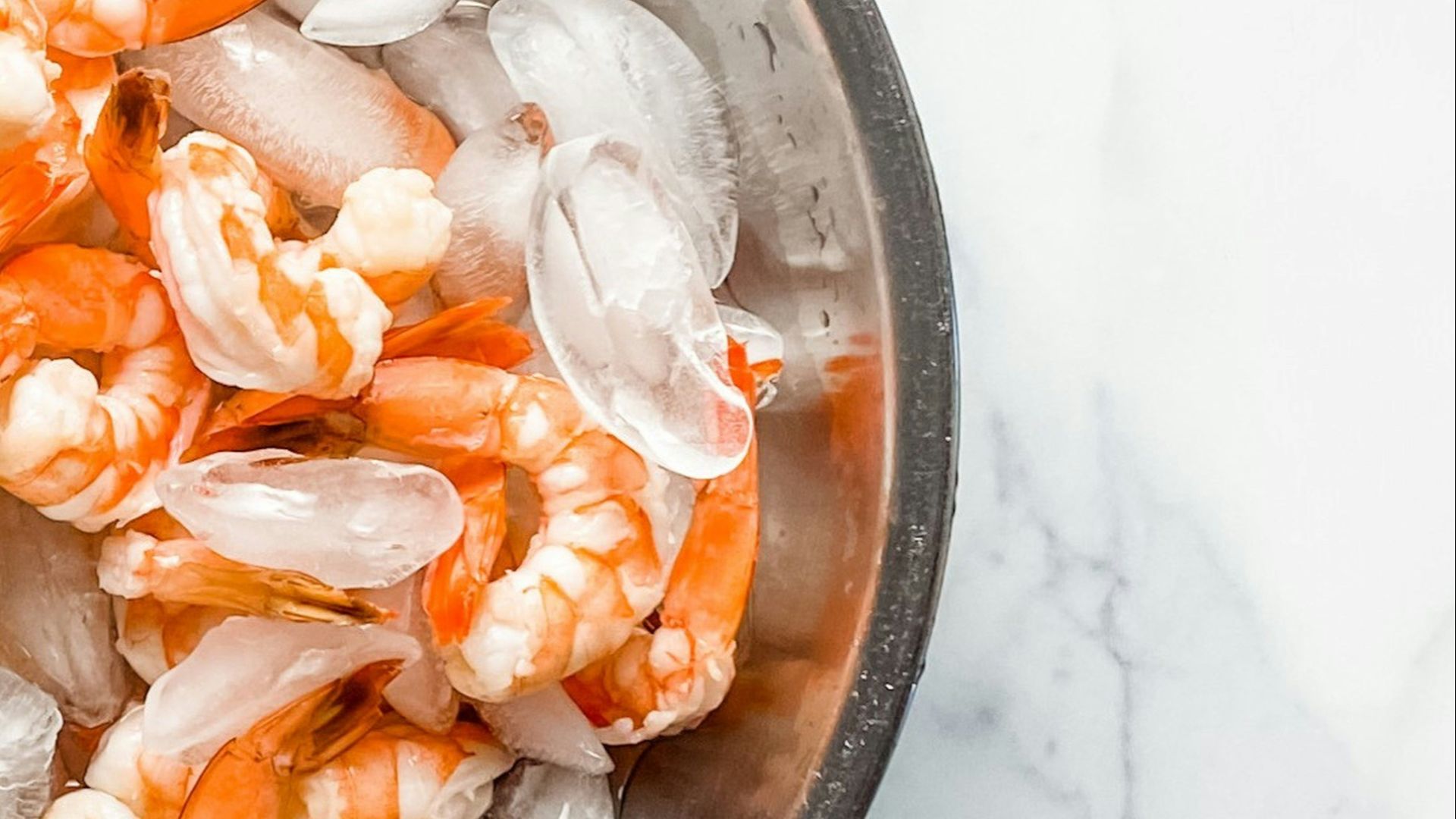 a metal bowl filled with shrimp on top of a table