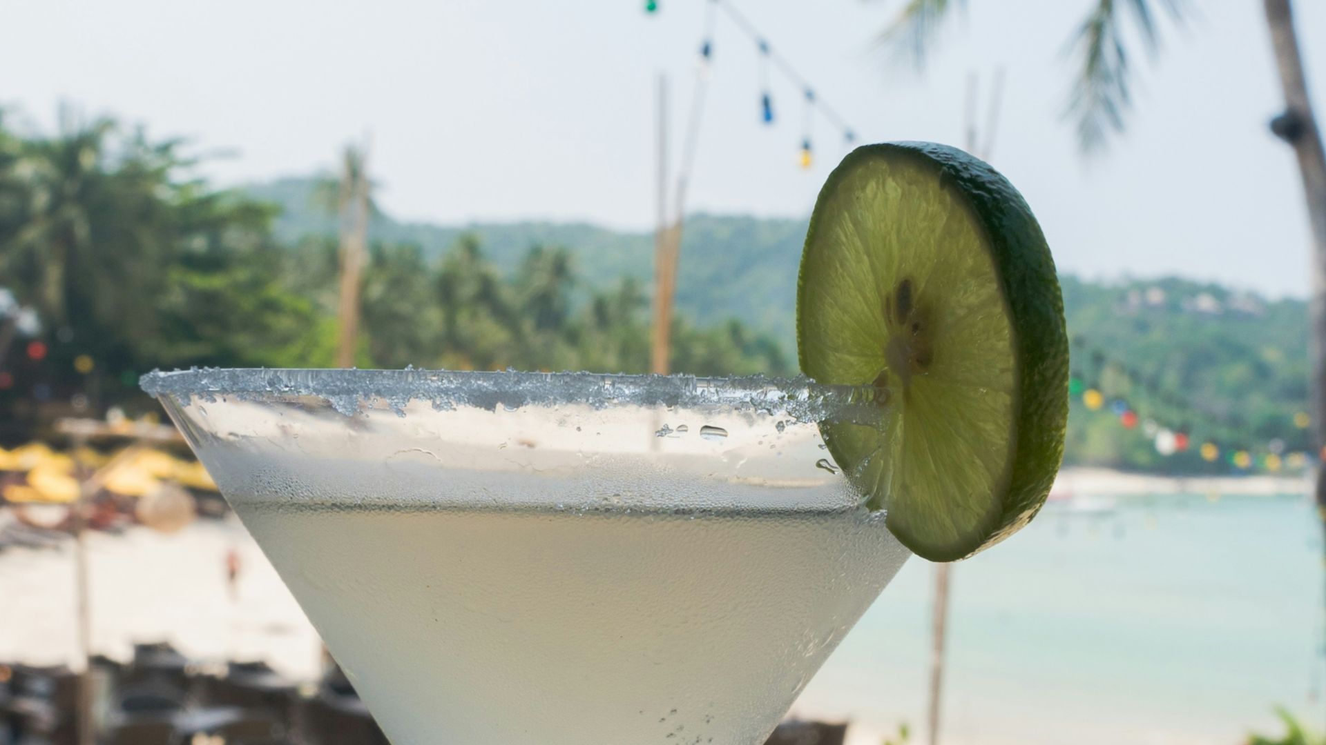 A cocktail sitting on top of a table next to a beach