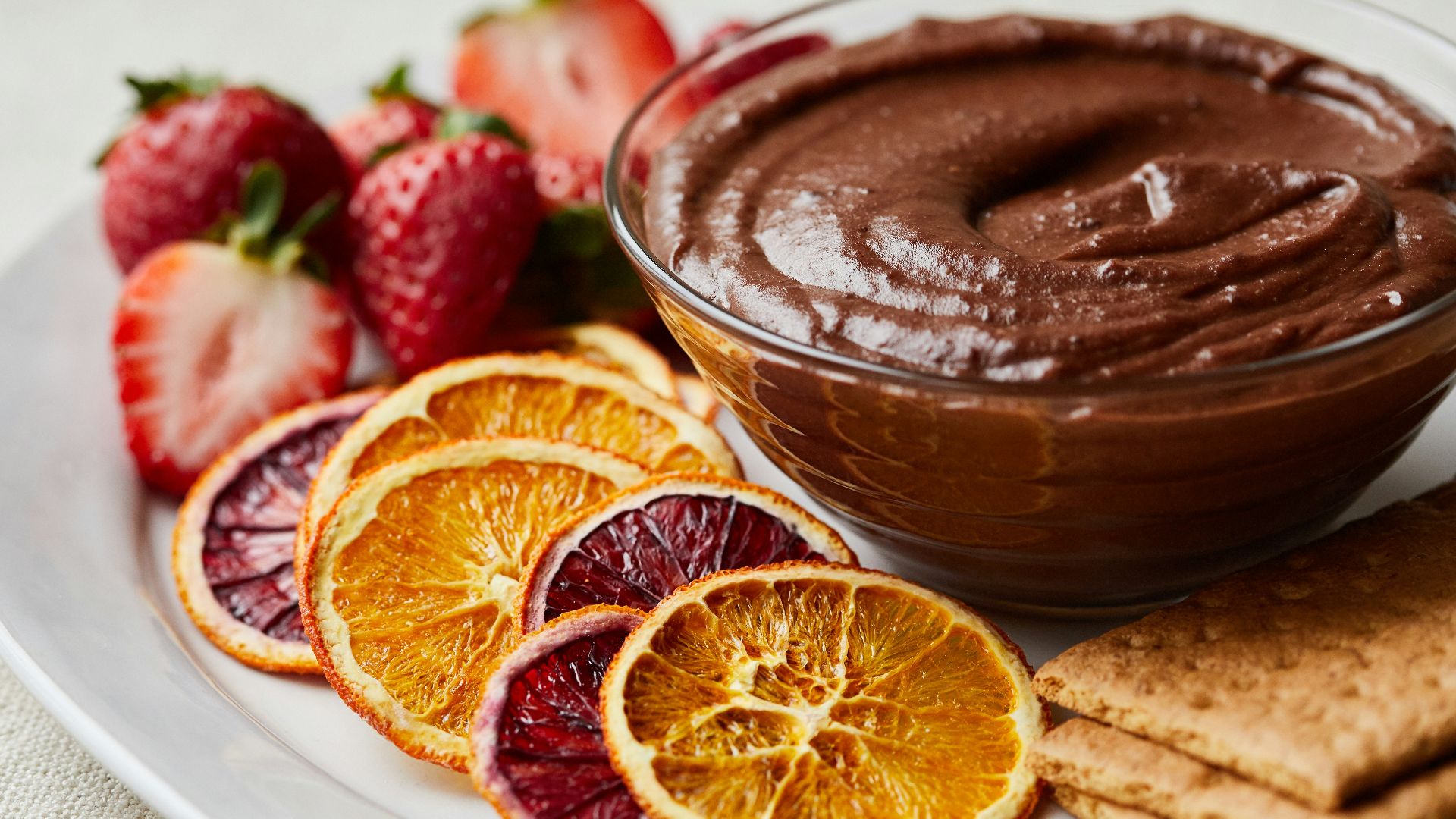 a white plate topped with fruit and a chocolate dip