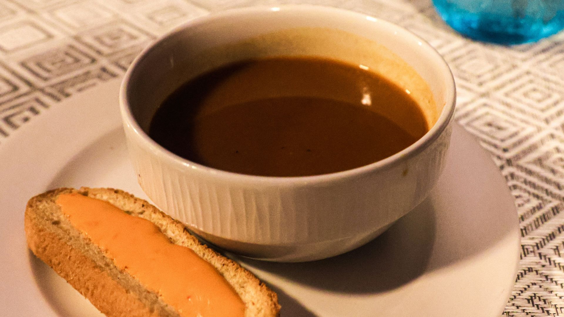 Soup and bread on a table, ready to eat.