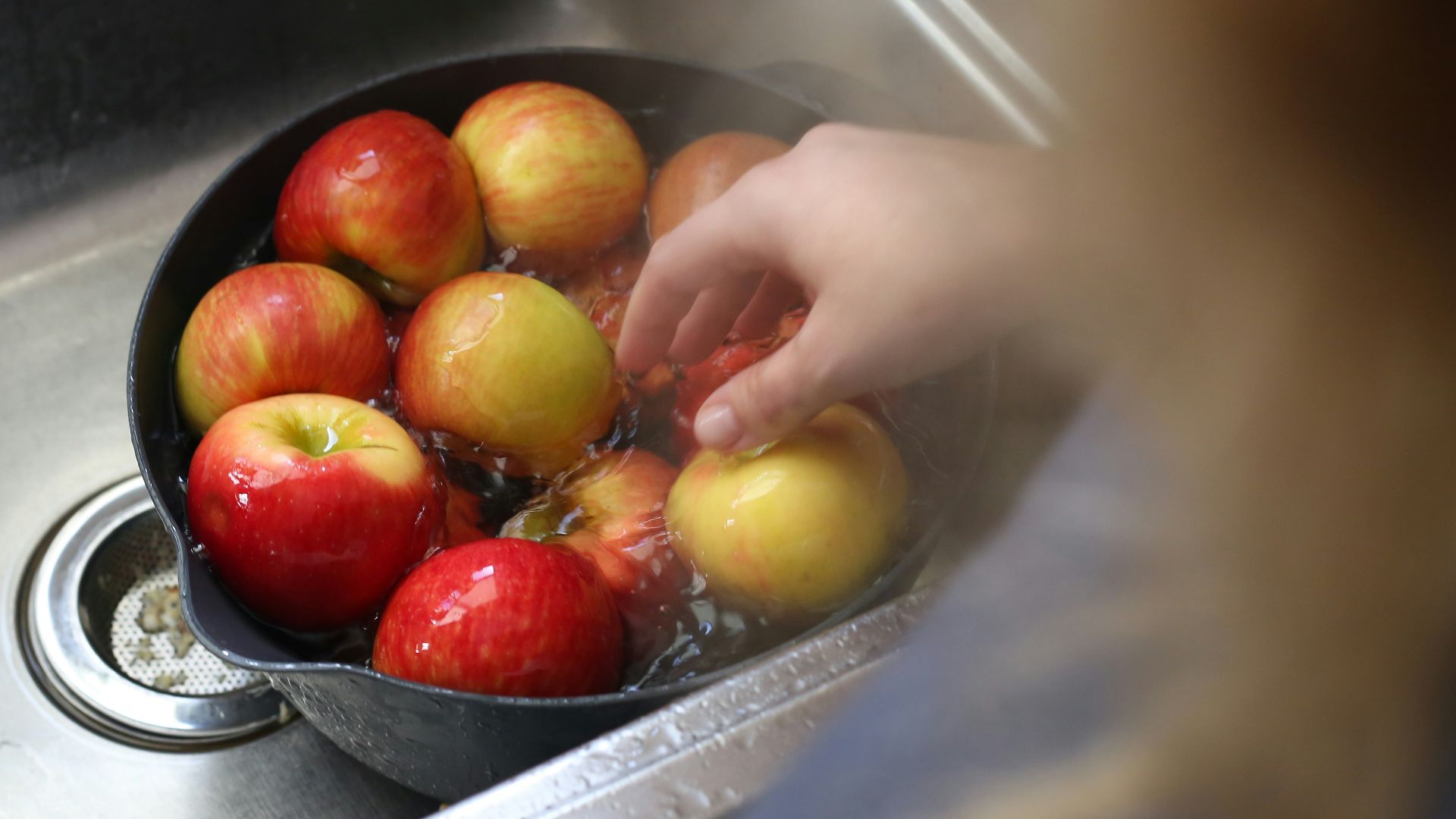 a person washing apples in a sink