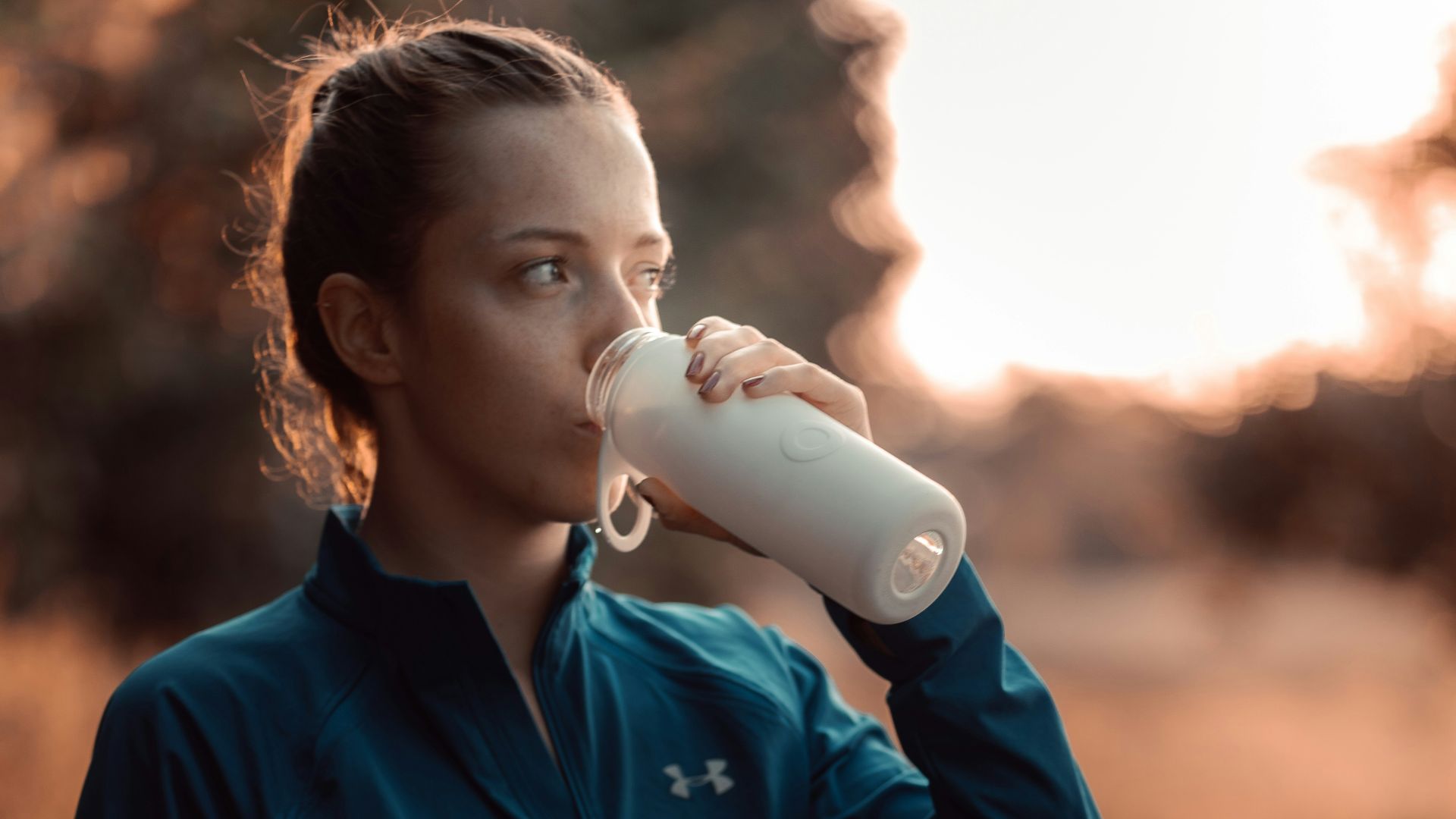 a woman is drinking from a water bottle