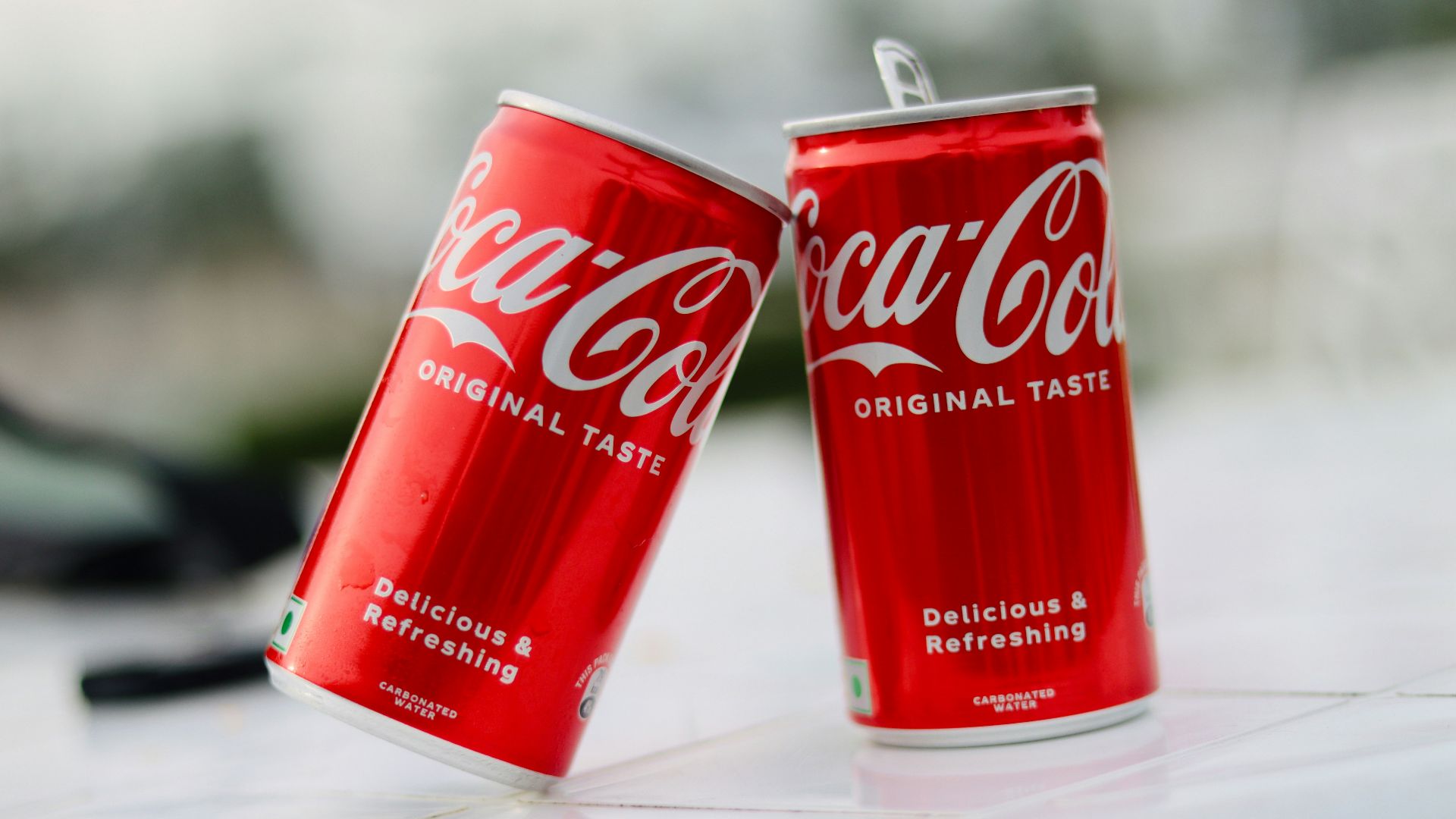 two cans of coca cola sitting on a table