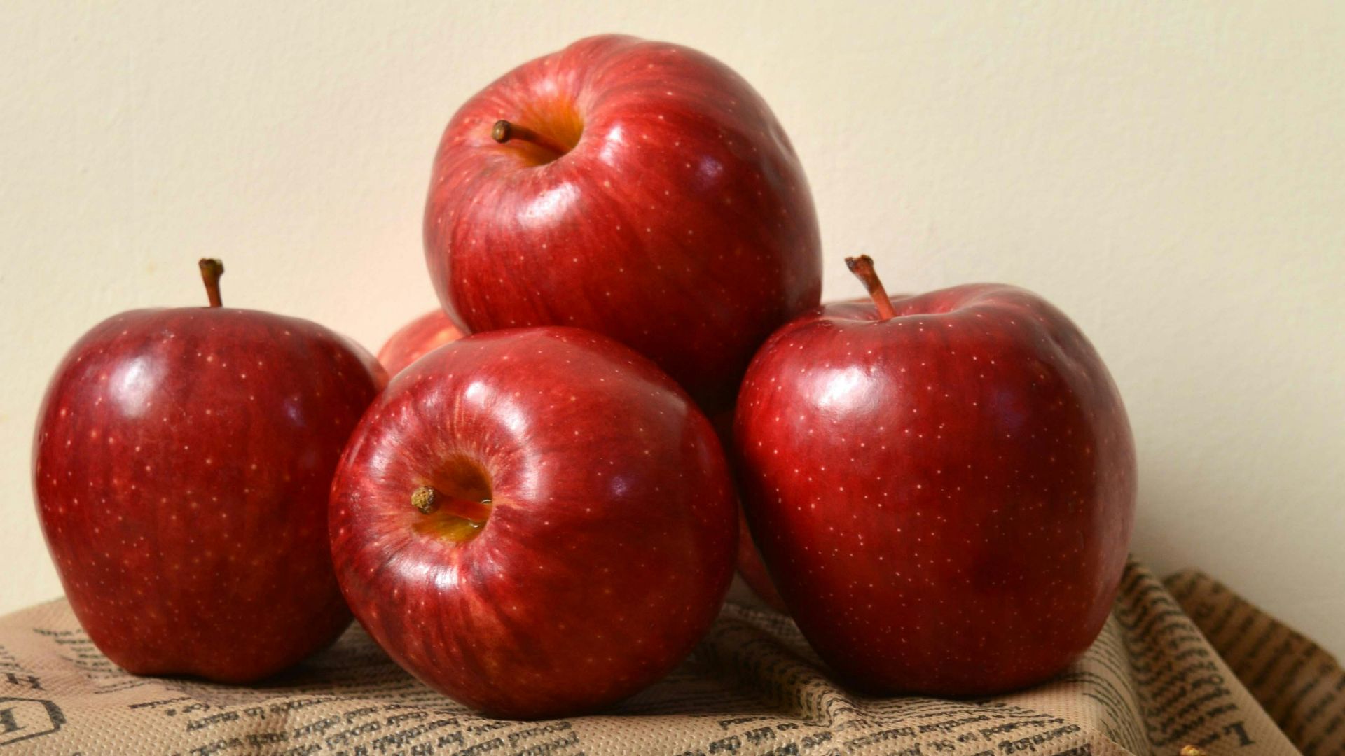 a pile of red apples sitting on top of a newspaper