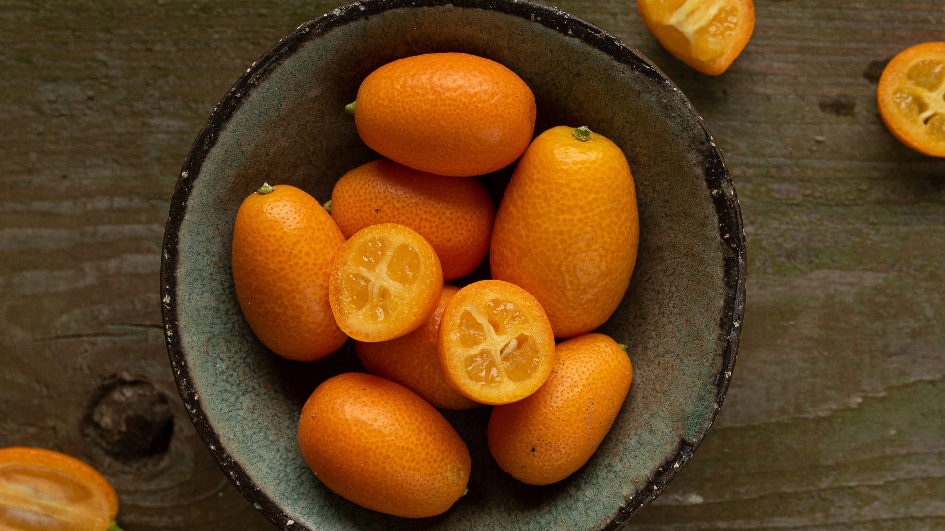 a bowl filled with oranges on top of a wooden table