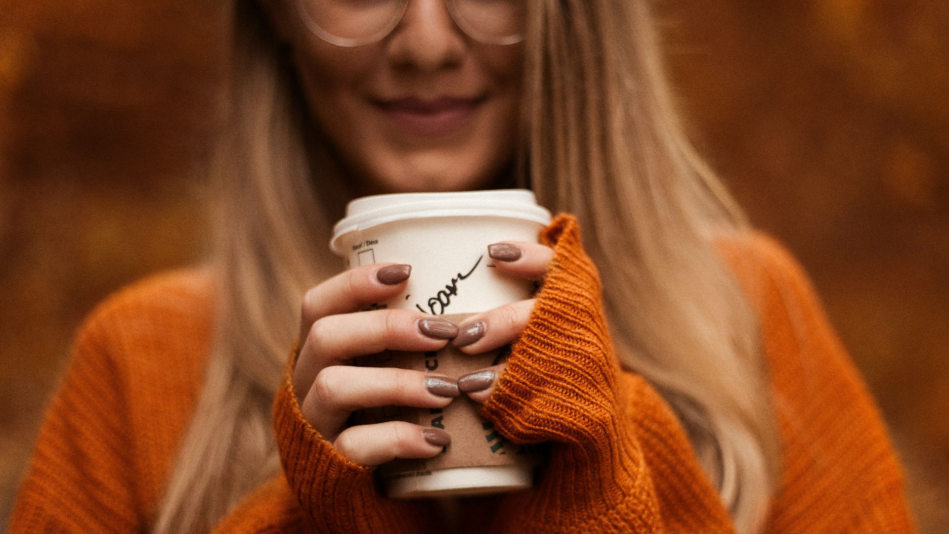 smiling woman standing and holding coffee cup with lid