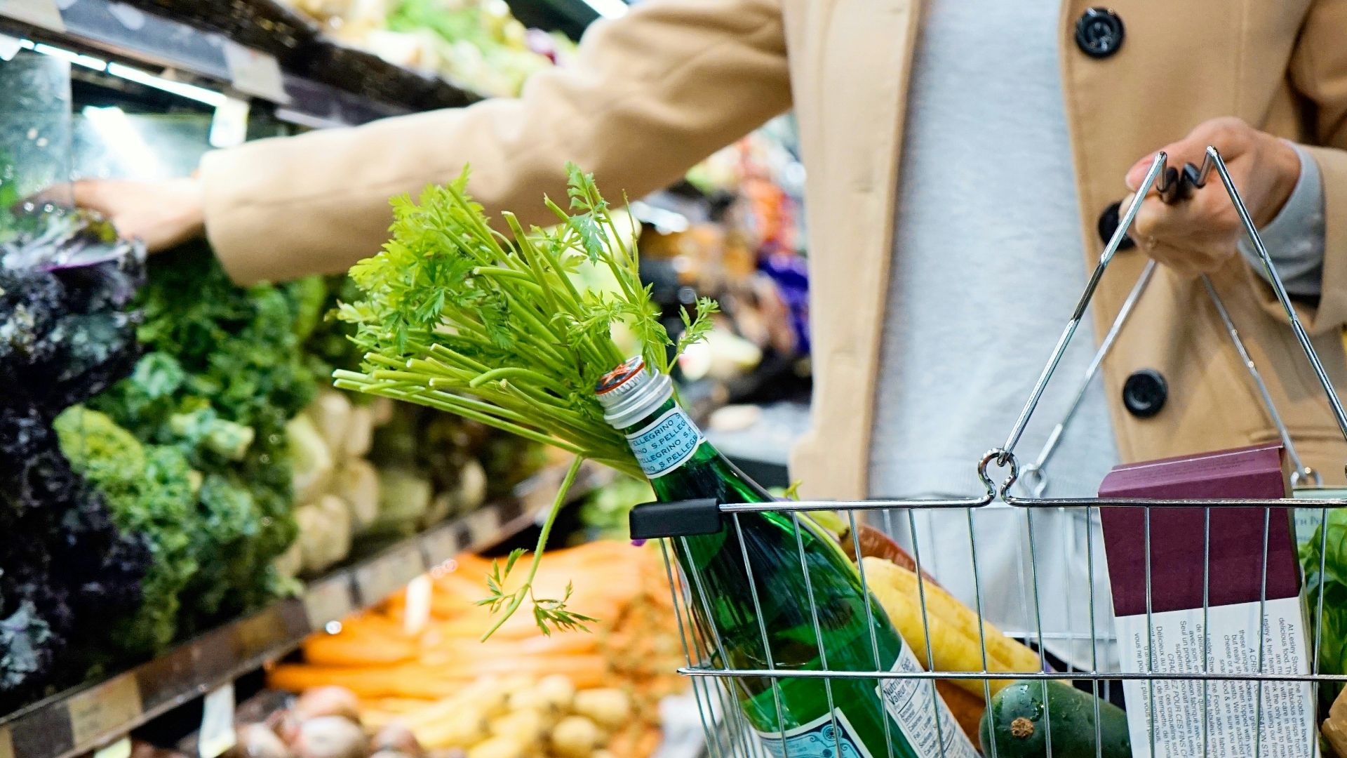 woman in white coat holding green shopping cart