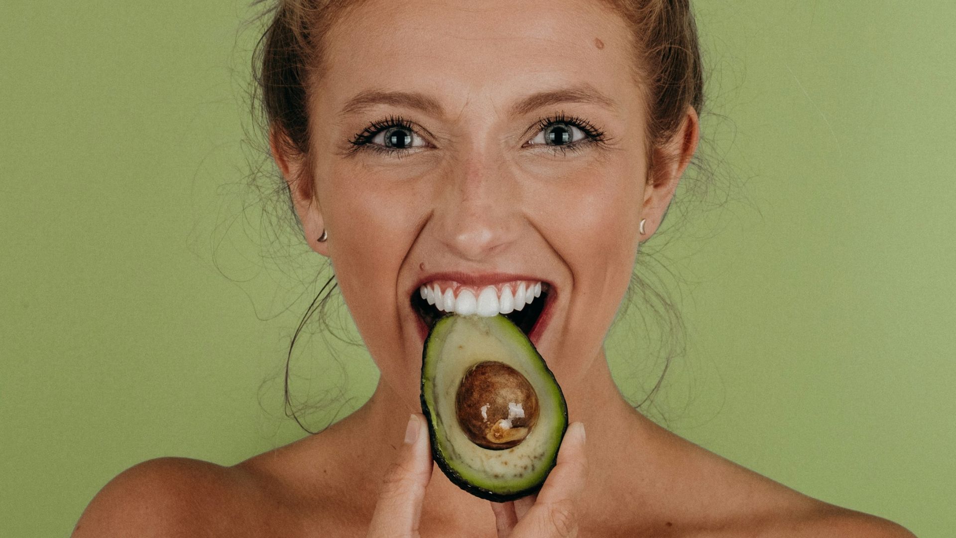 woman holding sliced avocado
