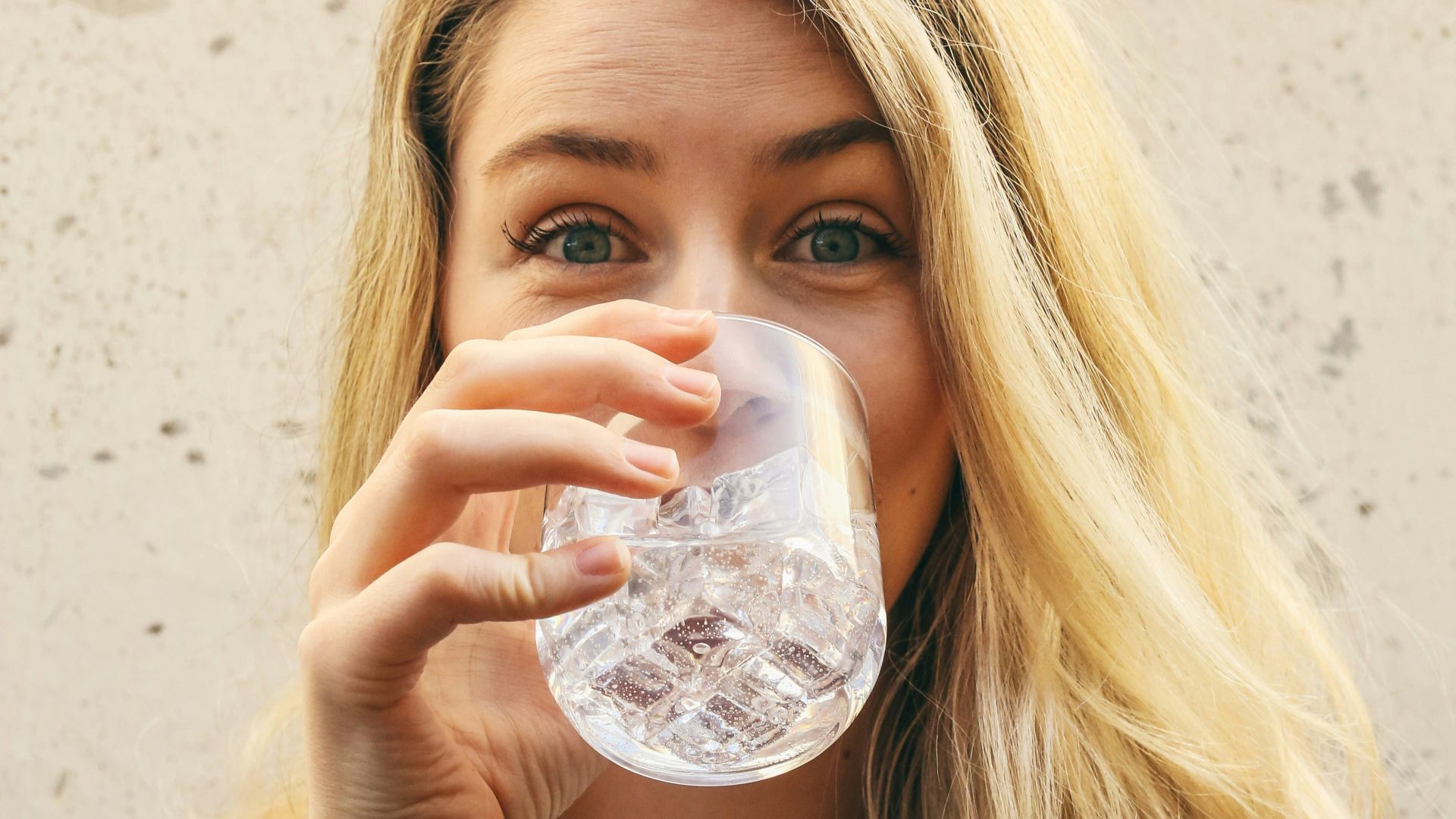 woman in white crew neck shirt drinking water