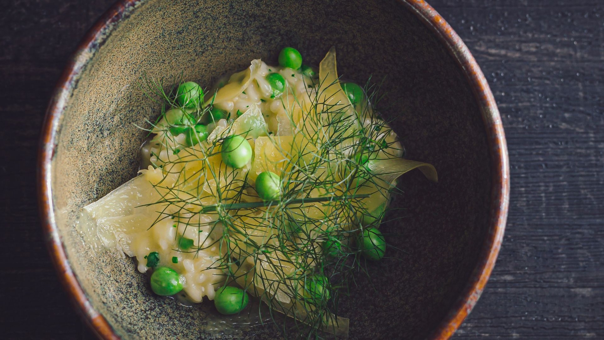 a bowl of food with peas on a wooden table