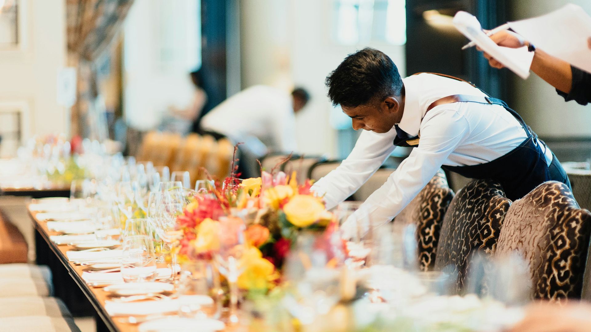 man in white top standing next to table