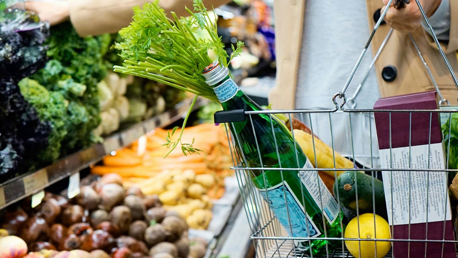 woman in white coat holding green shopping cart