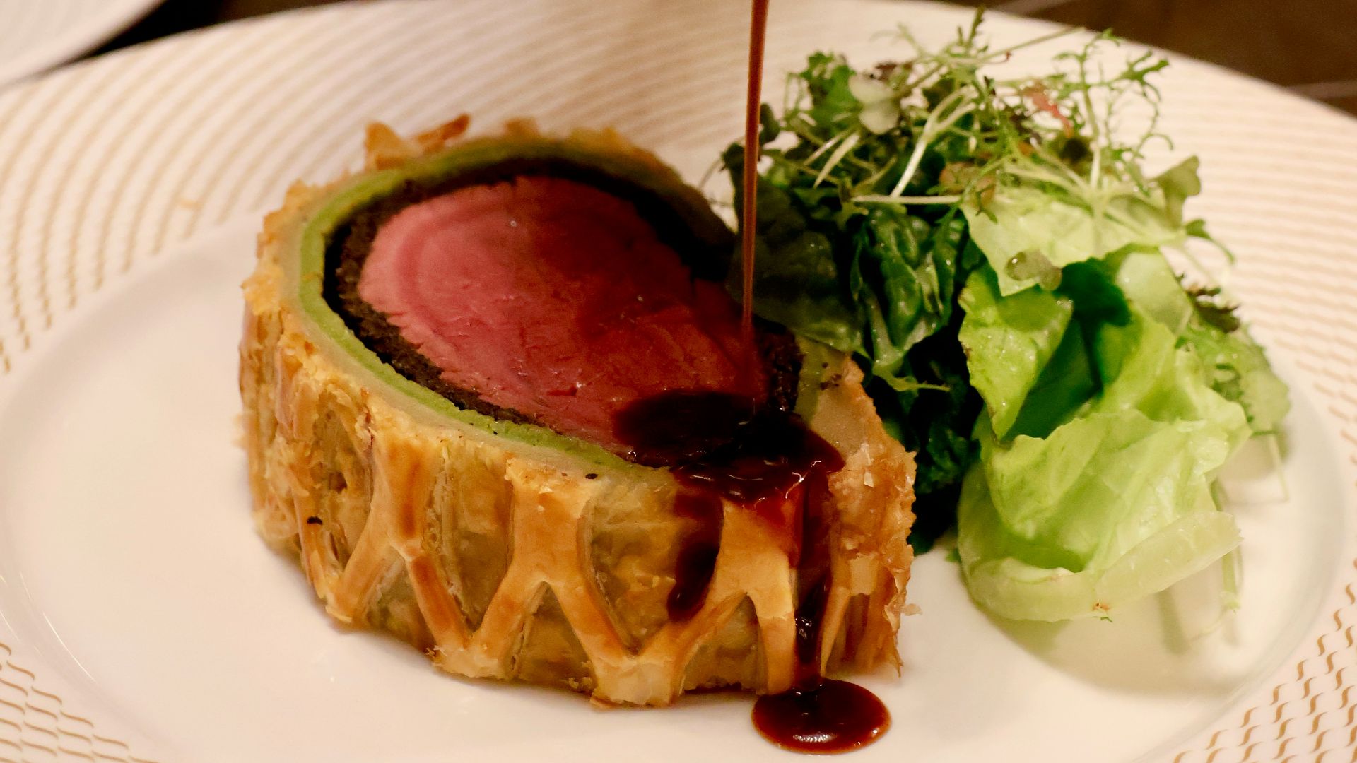 a person pouring sauce on a piece of meat