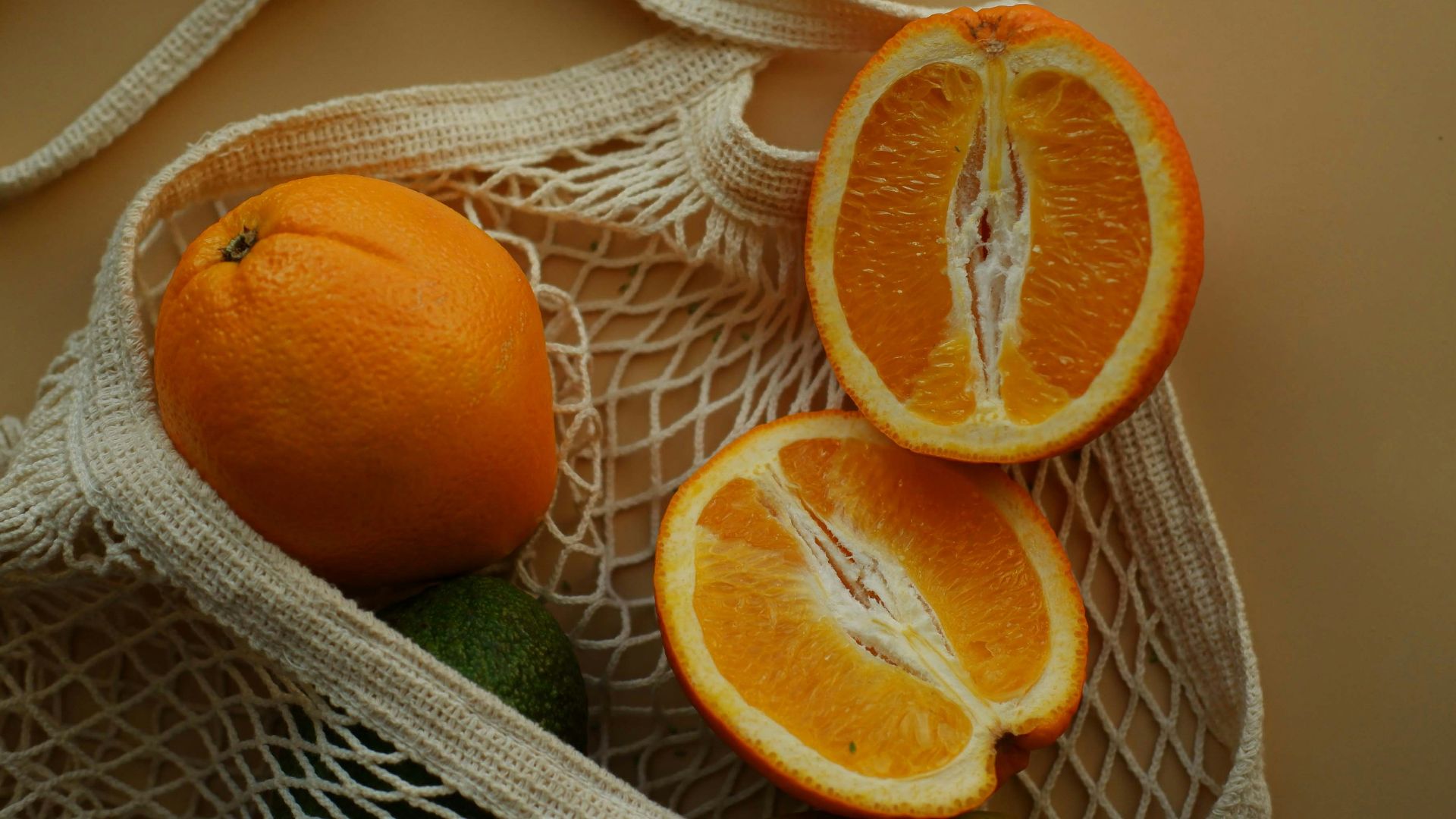 two oranges and one avocado in a bag