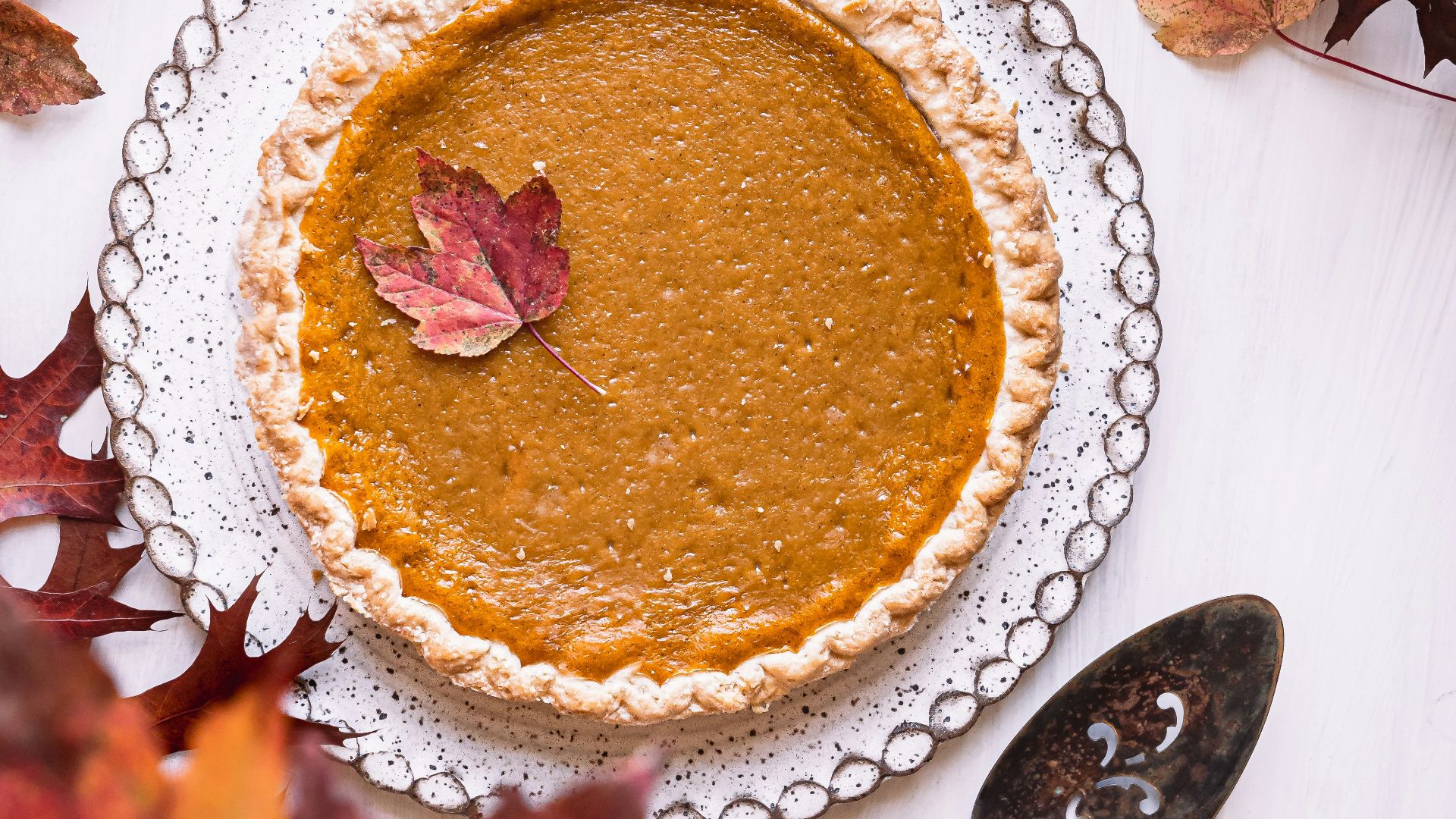 a pie sitting on top of a white table next to leaves
