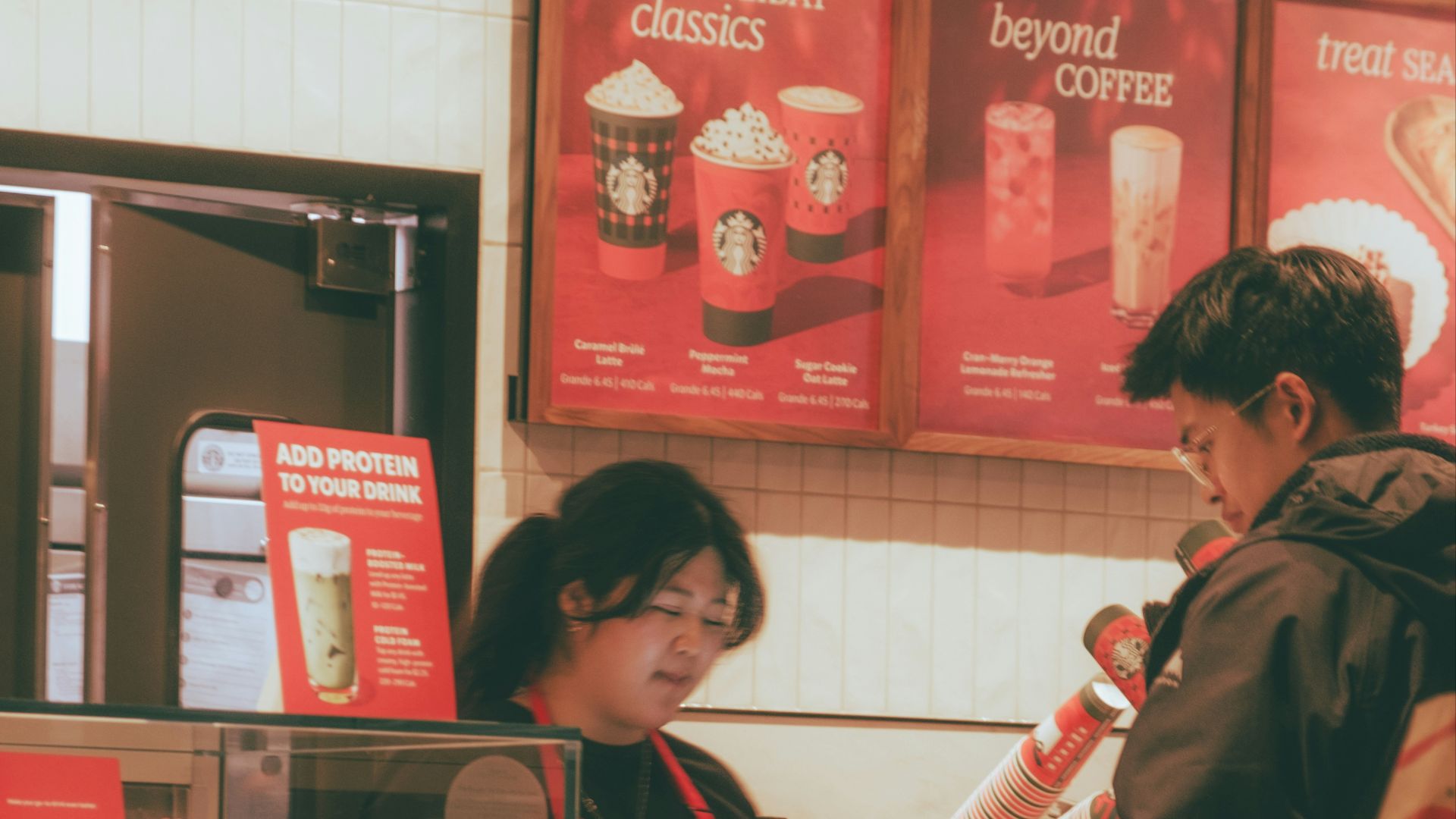 Barista serving customer at a coffee shop counter.