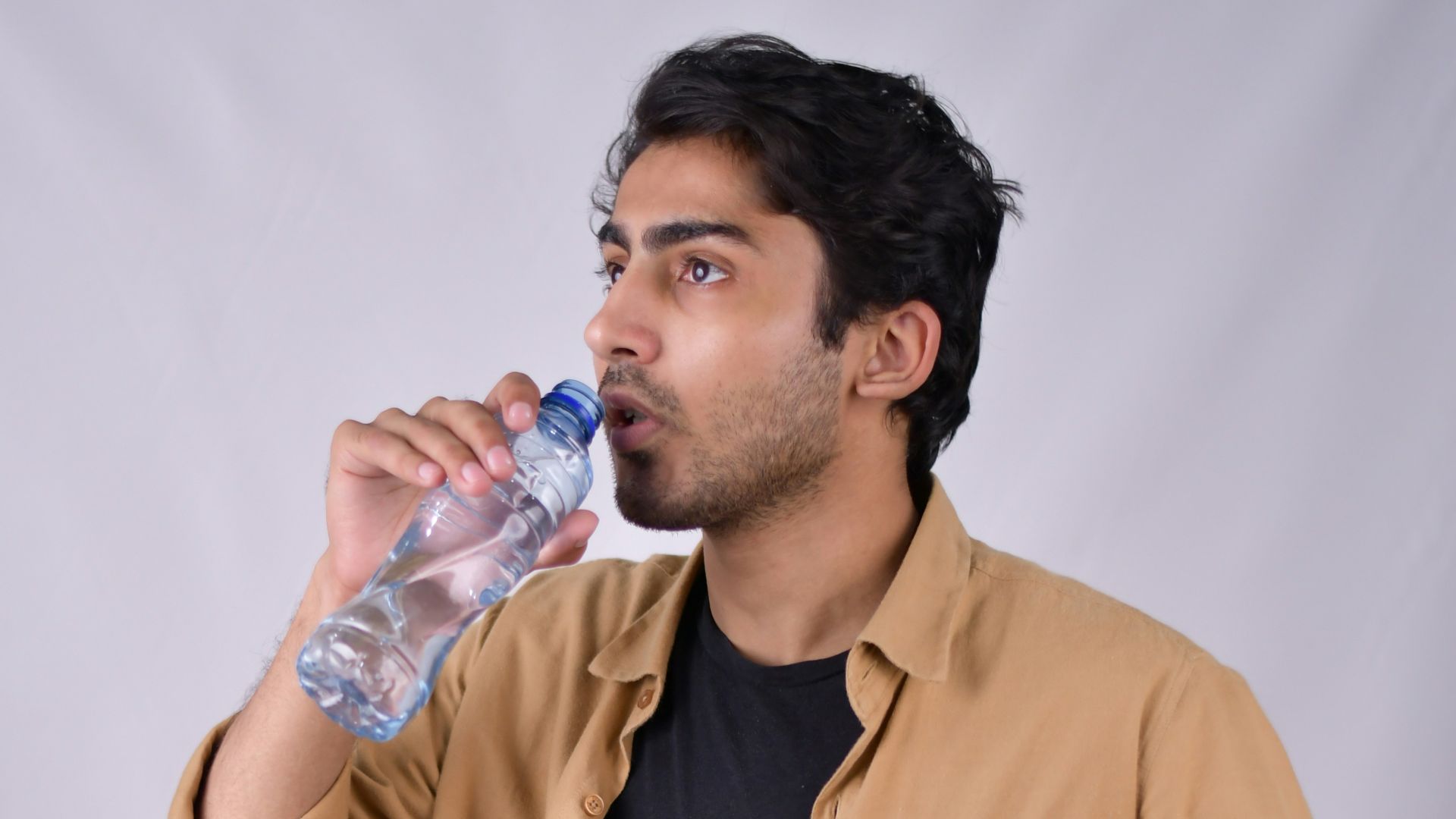a man is drinking water from a bottle