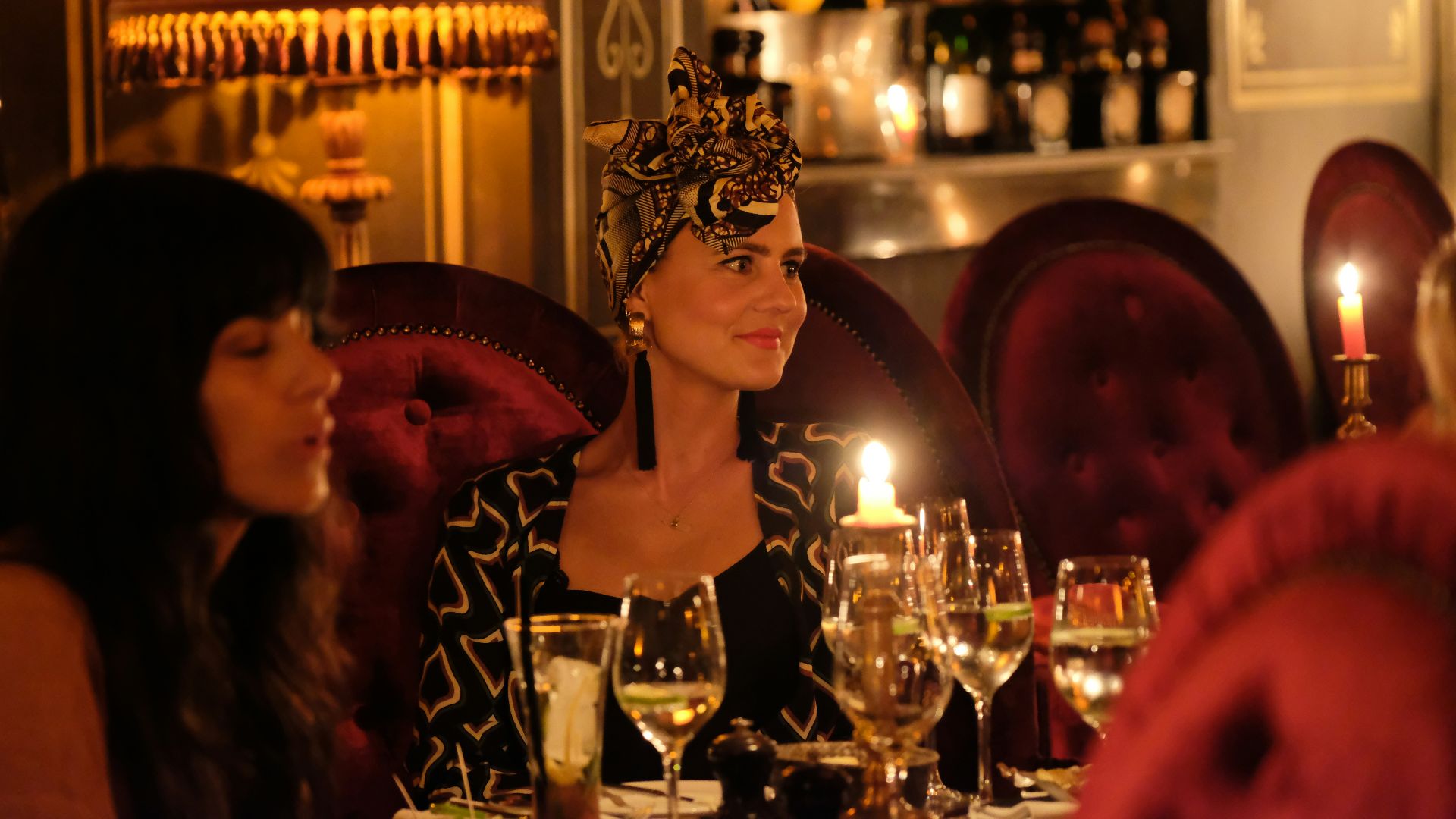 a woman sitting at a table with wine glasses