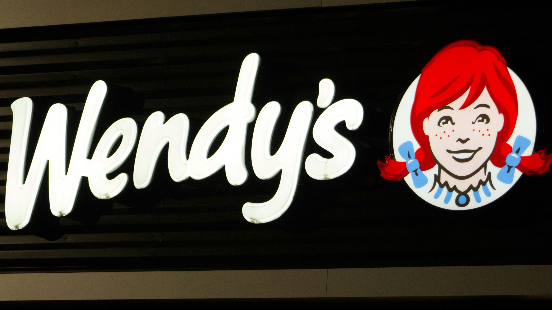A wendy's sign is lit up at night