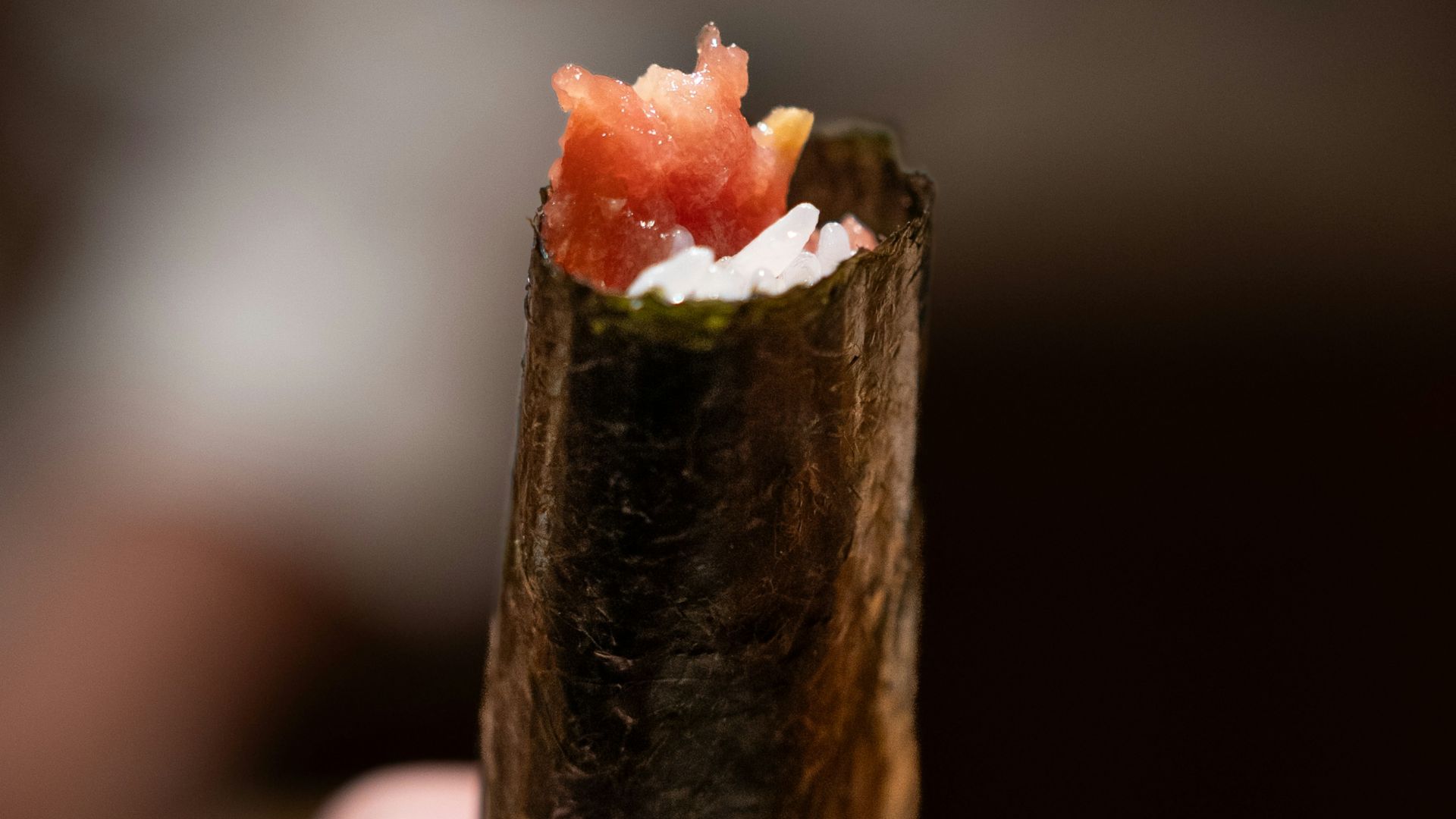 Hand holding a sushi roll filled with delicious fish.