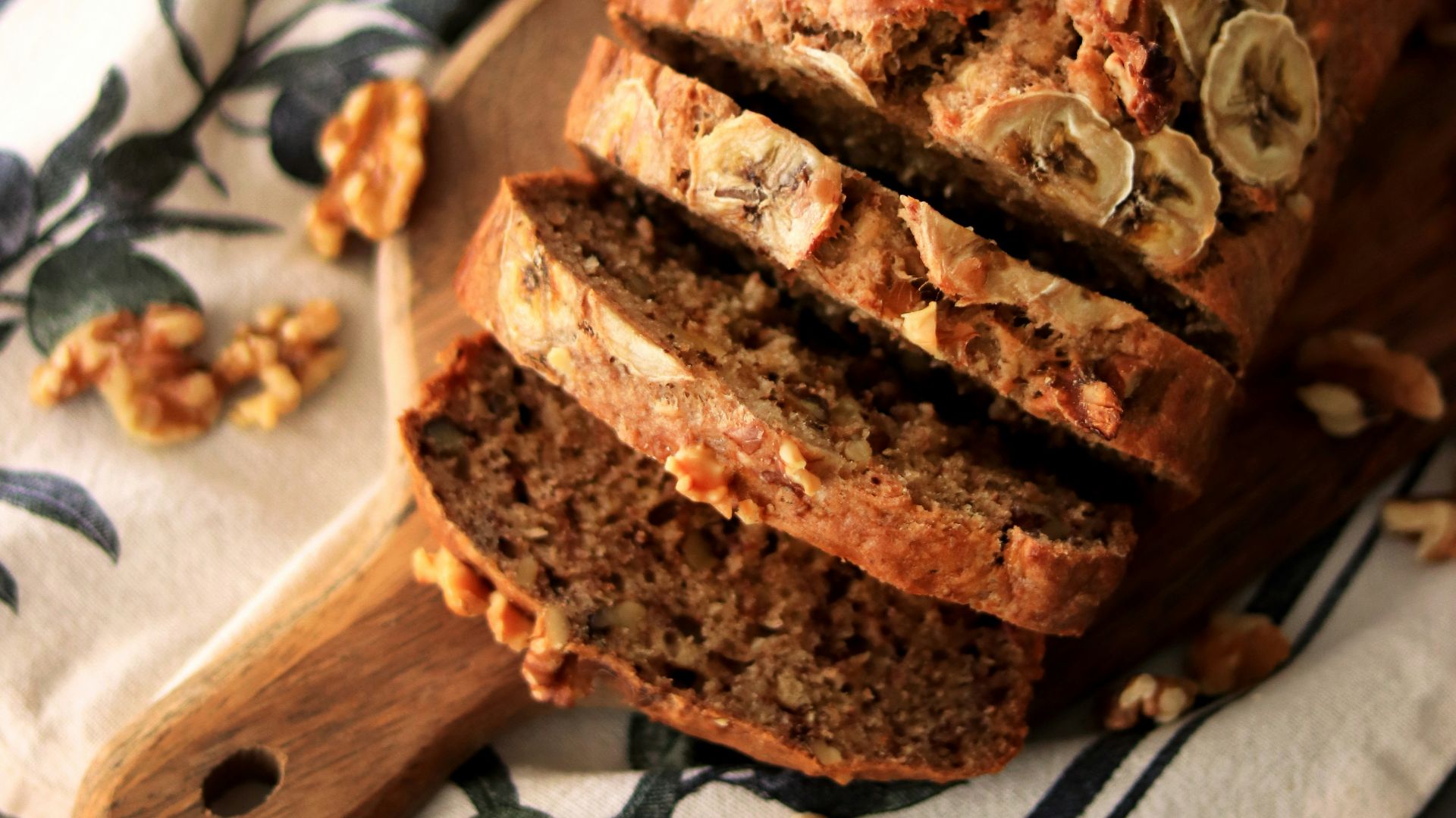 a loaf of banana nut bread sitting on top of a wooden cutting board