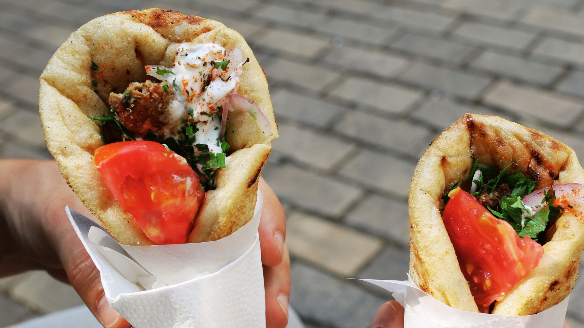 A person holding two sandwiches in their hands