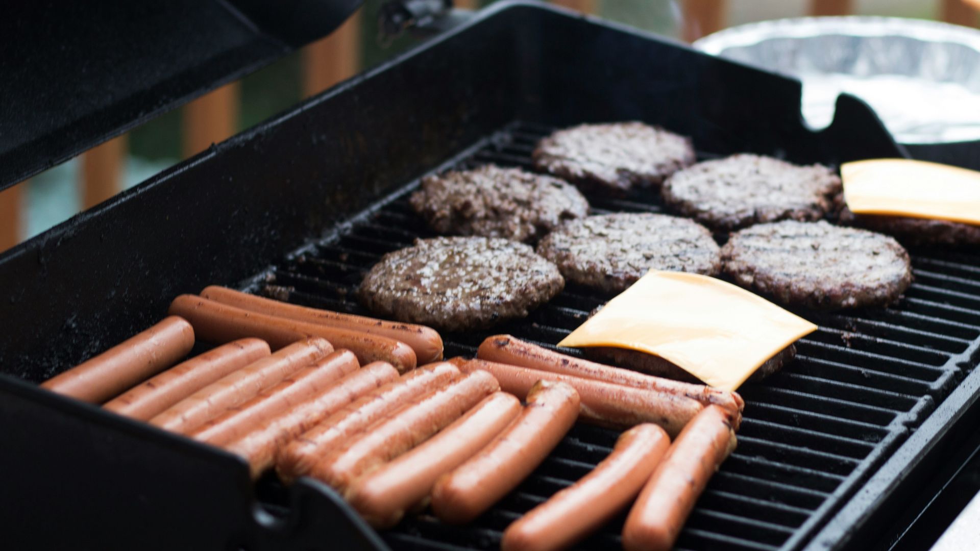 person standing in front grill grilling sausage