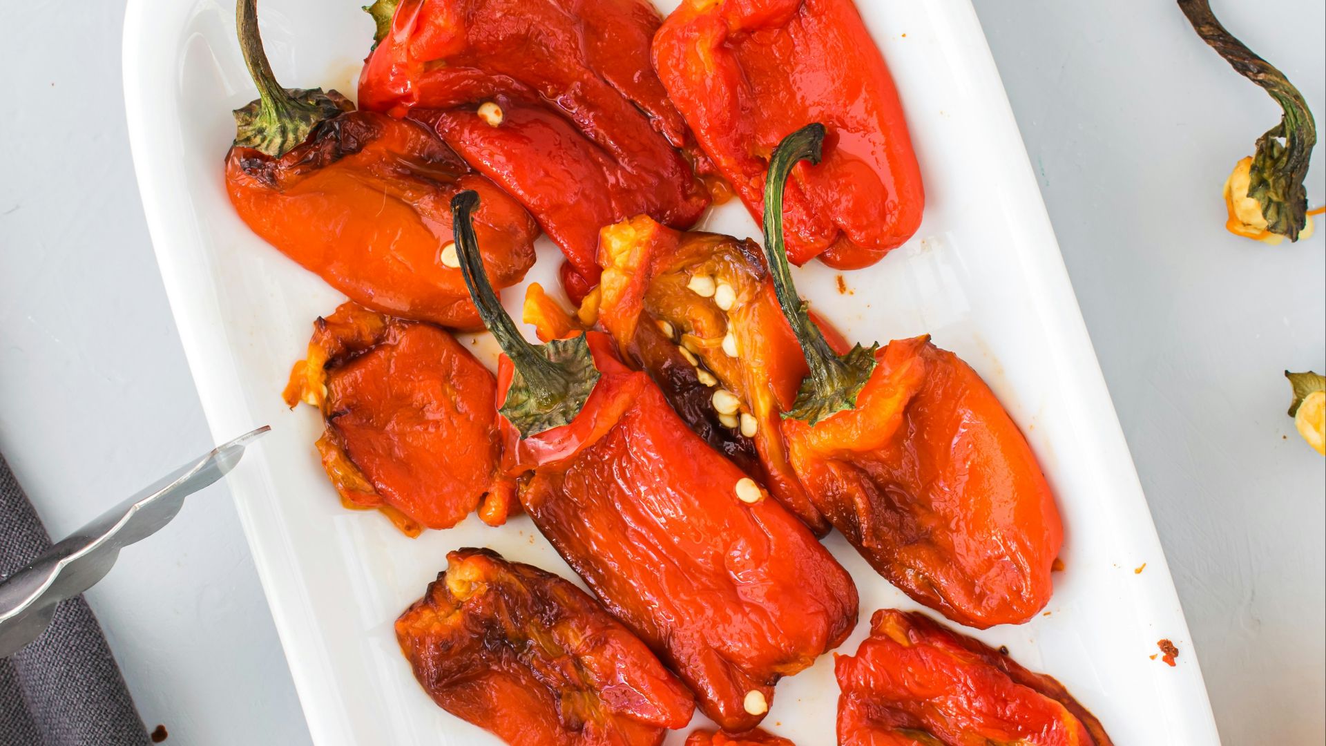 a white plate topped with red peppers next to other plates of food